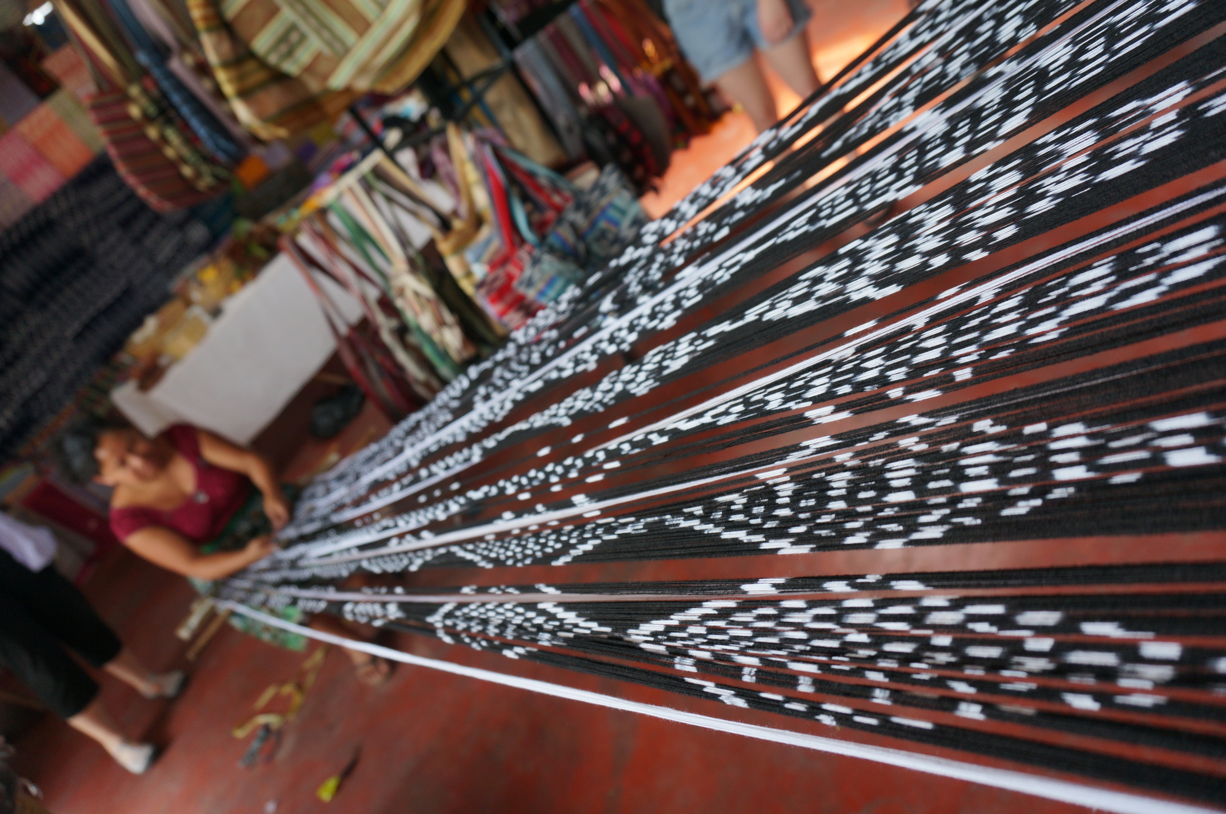A weaver working on her piece; threads are dyed before they are placed onto the loom.