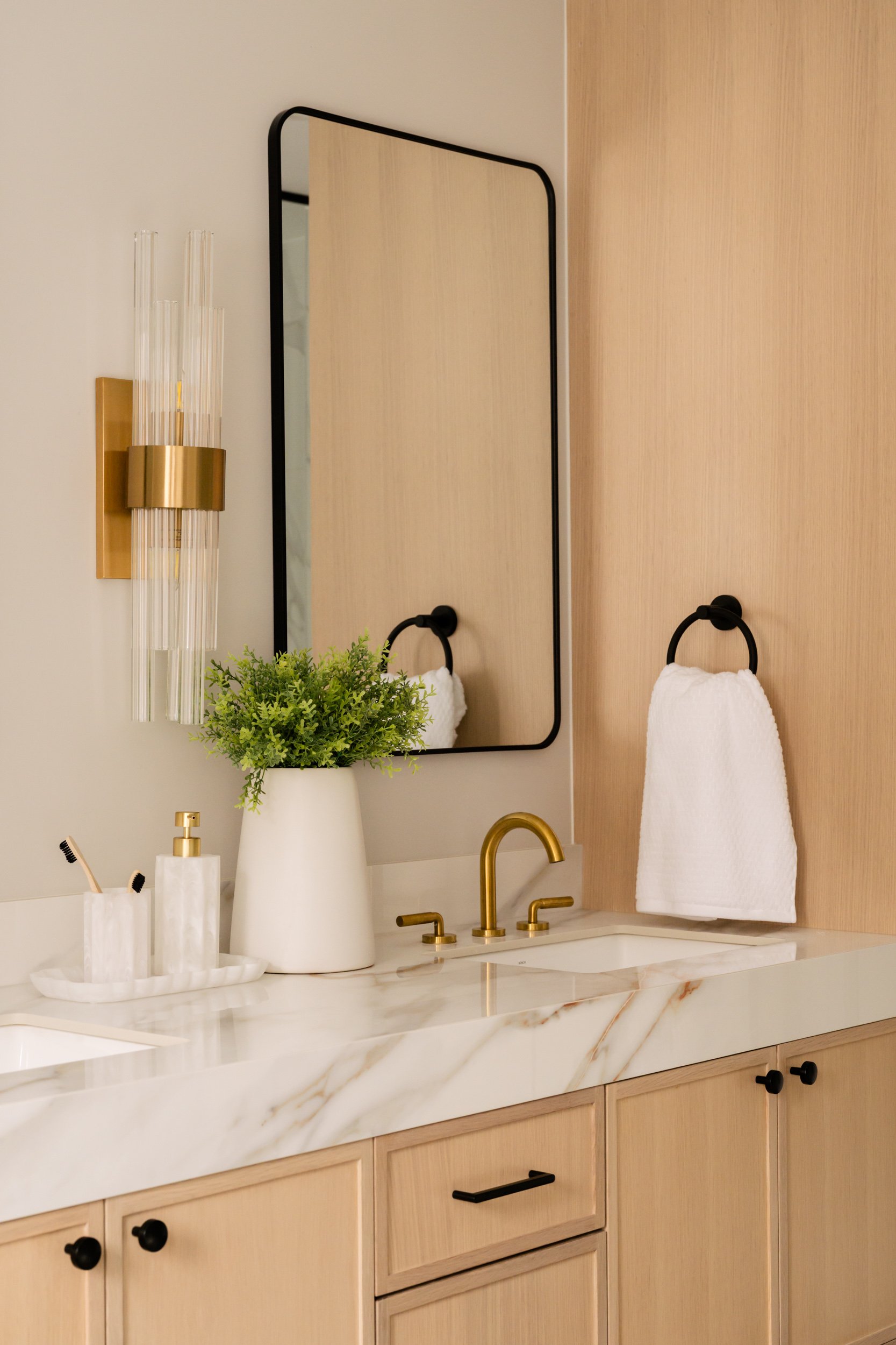 A close up of a vanity with gold faucets in a bathroom.