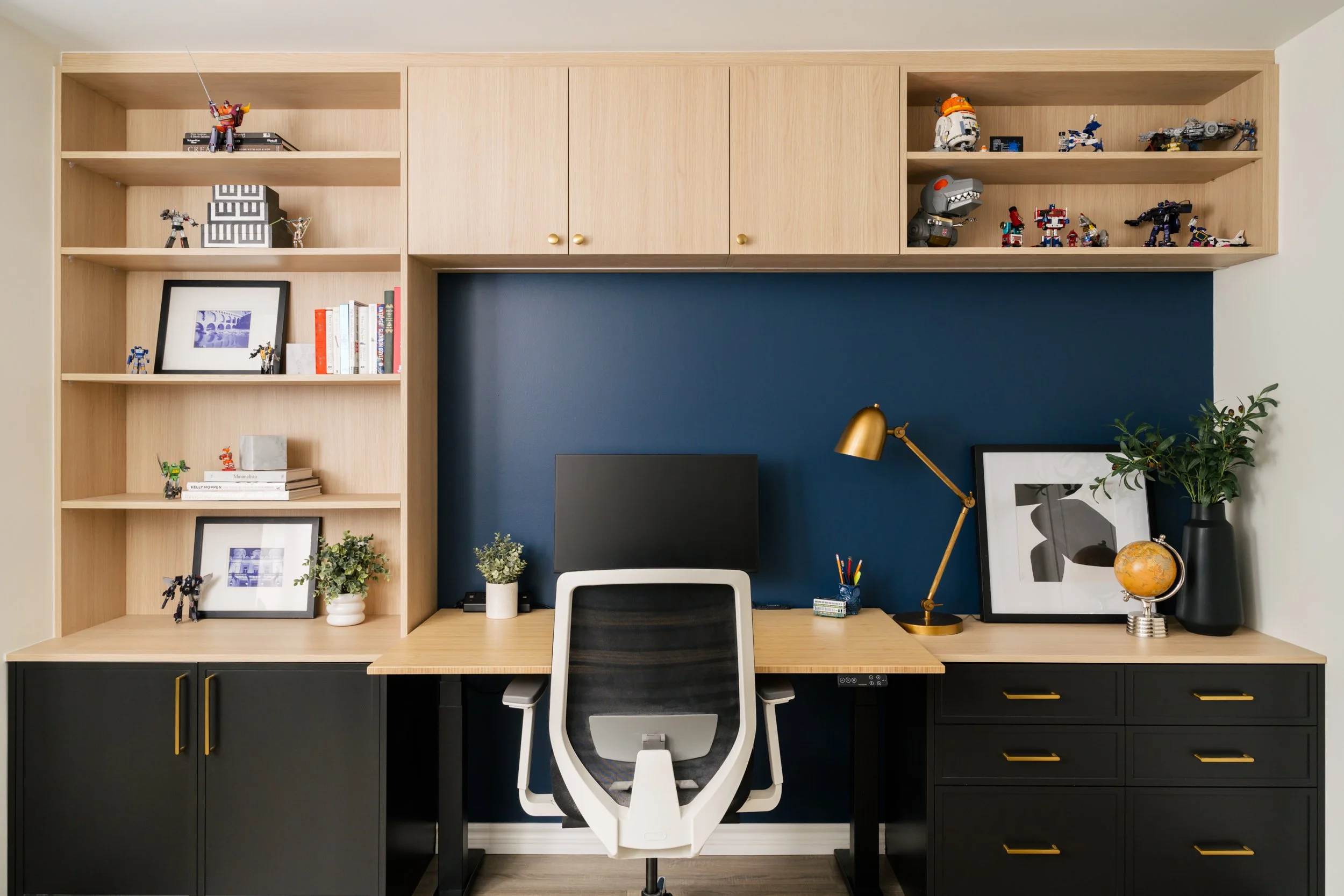 Home office with built-in shelves and a height-adjustable desk. The wall behind the desk is painted blue.