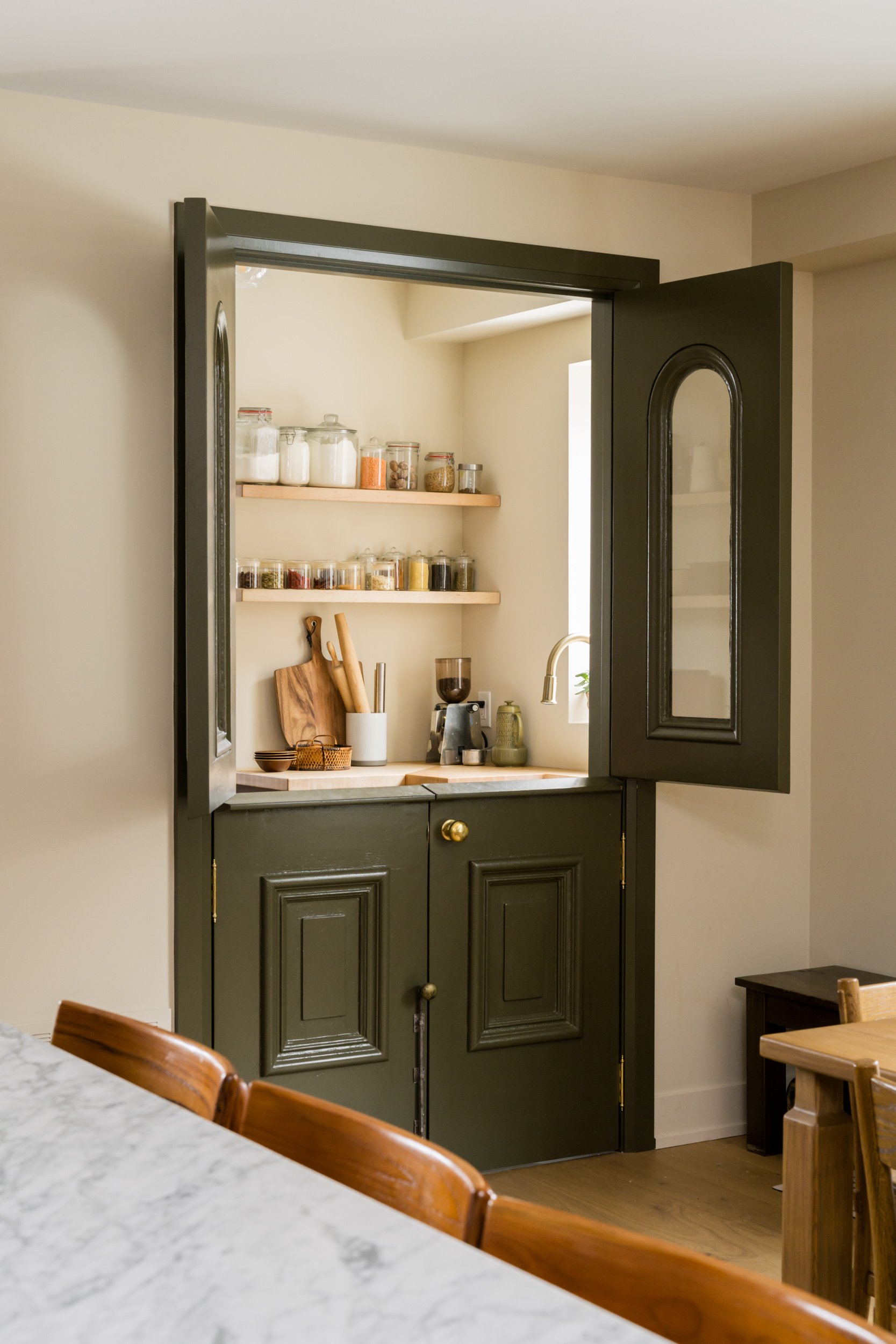 Sage green Dutch doors to a pantry partially open
