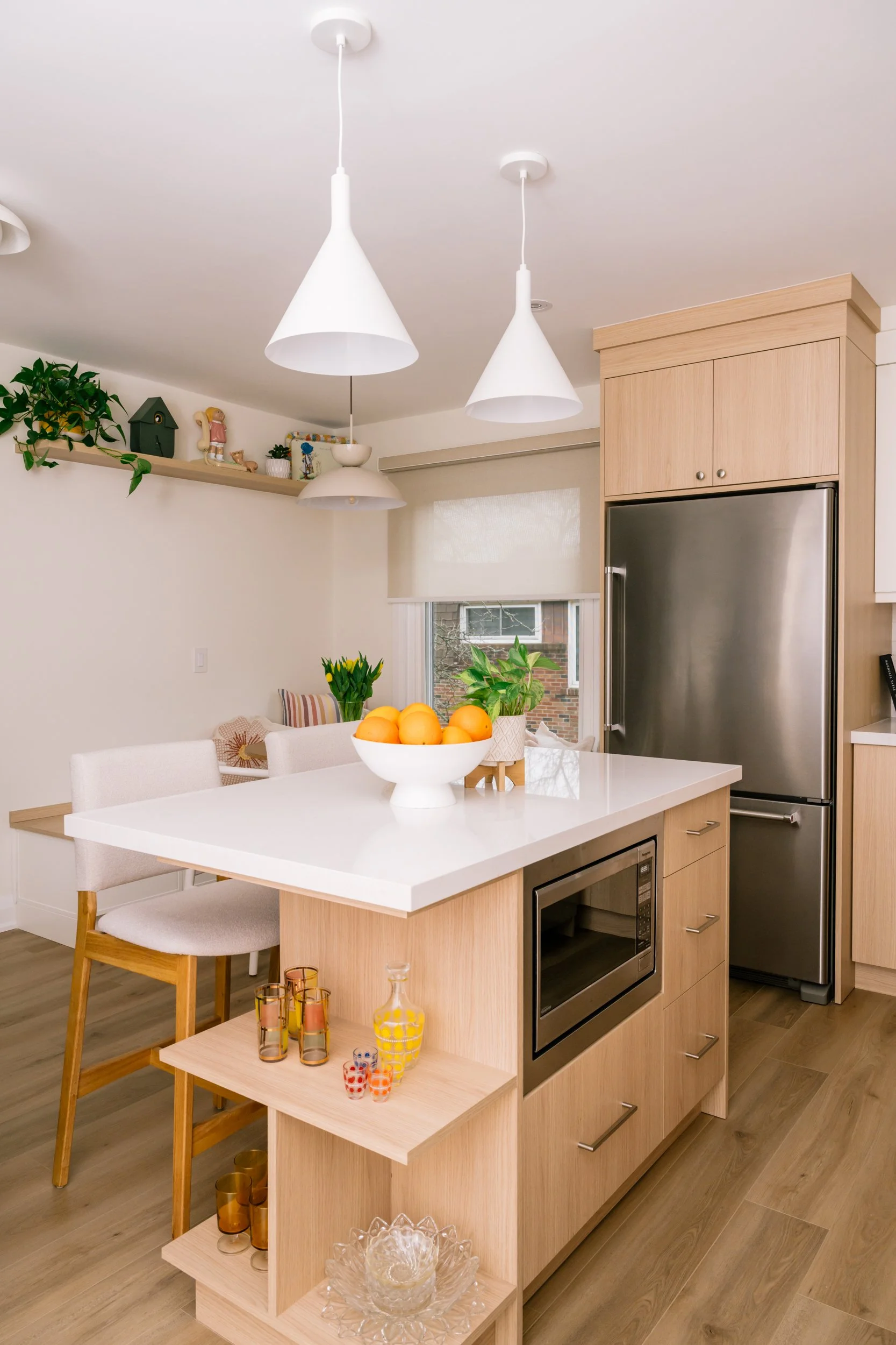 A small kitchen island stands in the middle of a kitchen with two white pendant lights above