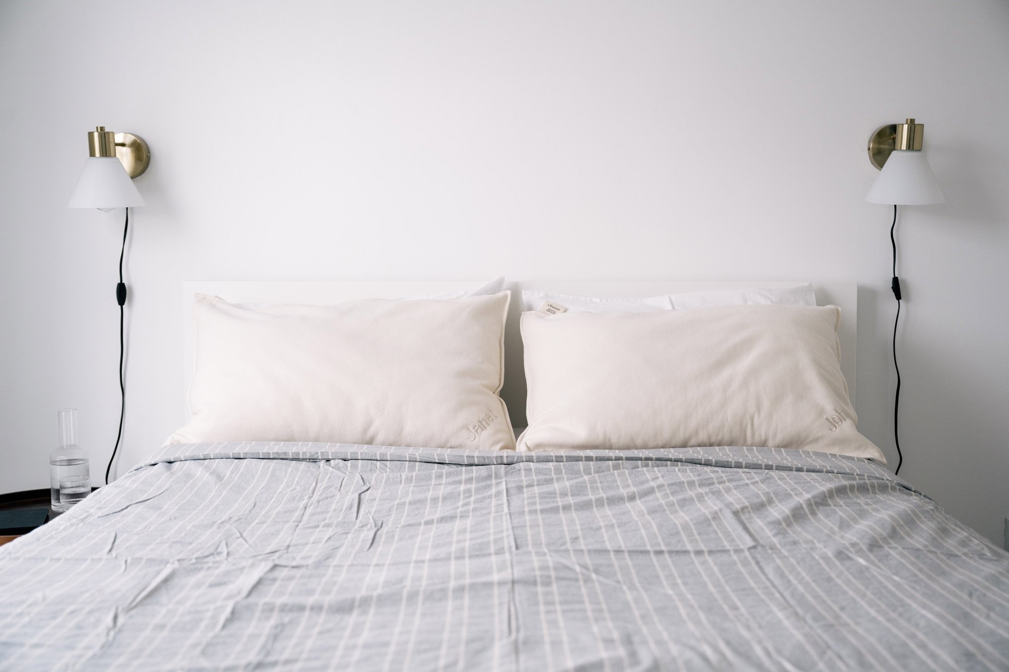 A bed sits between two wall sconces with Obasan pillows on the bed.