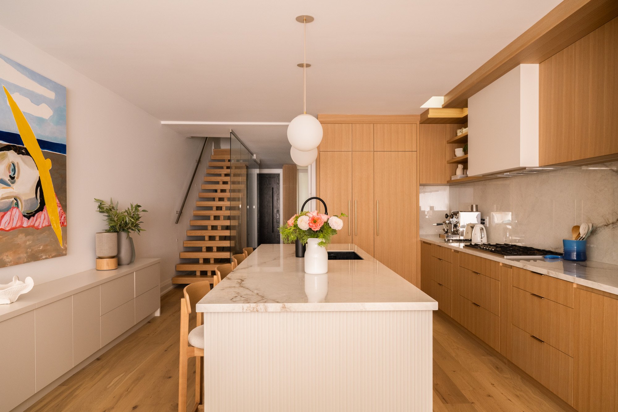 A wide view of a kitchen with a long island and cabinets on both sides of the island.