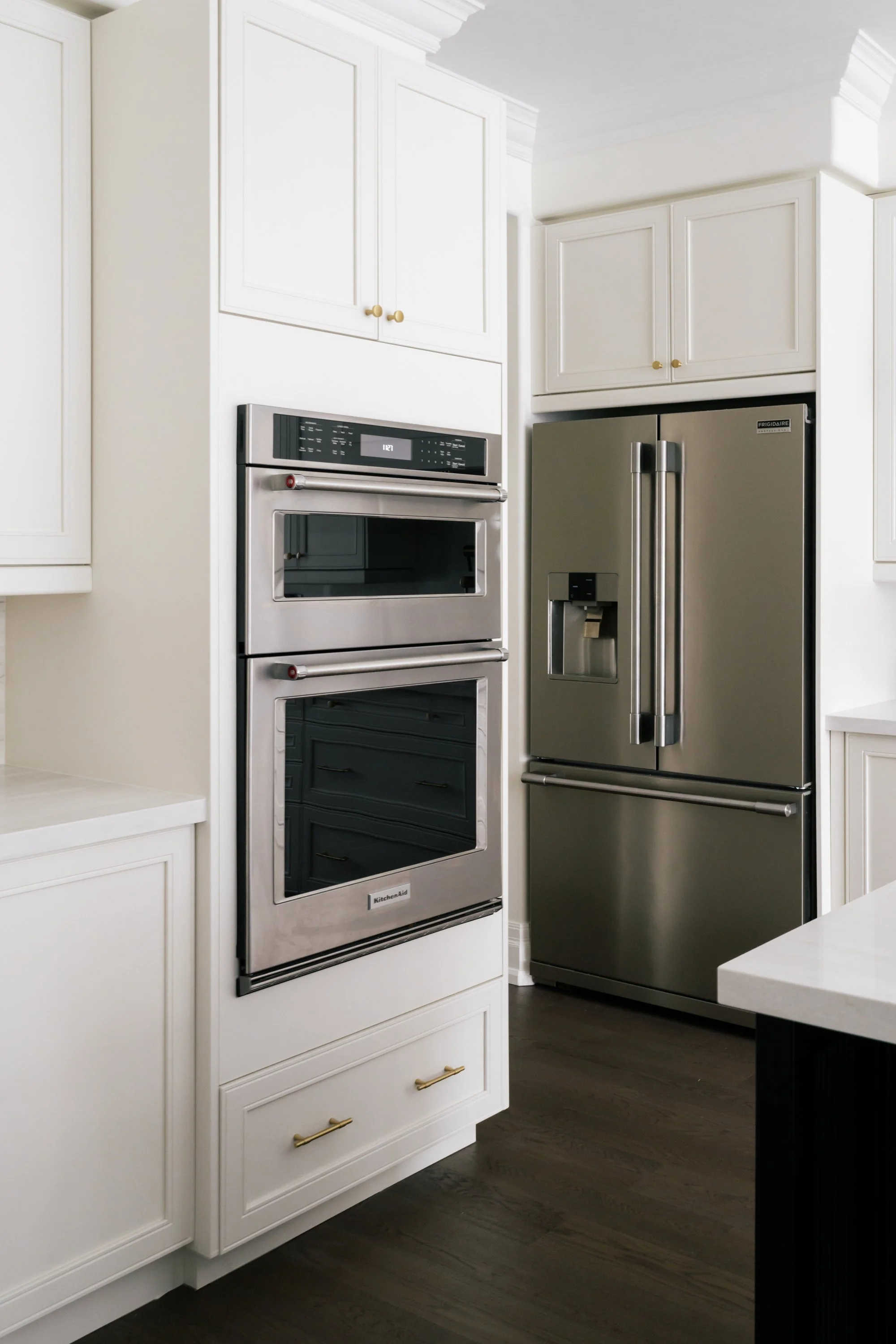 A view of kitchen appliances. An integrated oven on one wall and a large refrigerator in another wall.