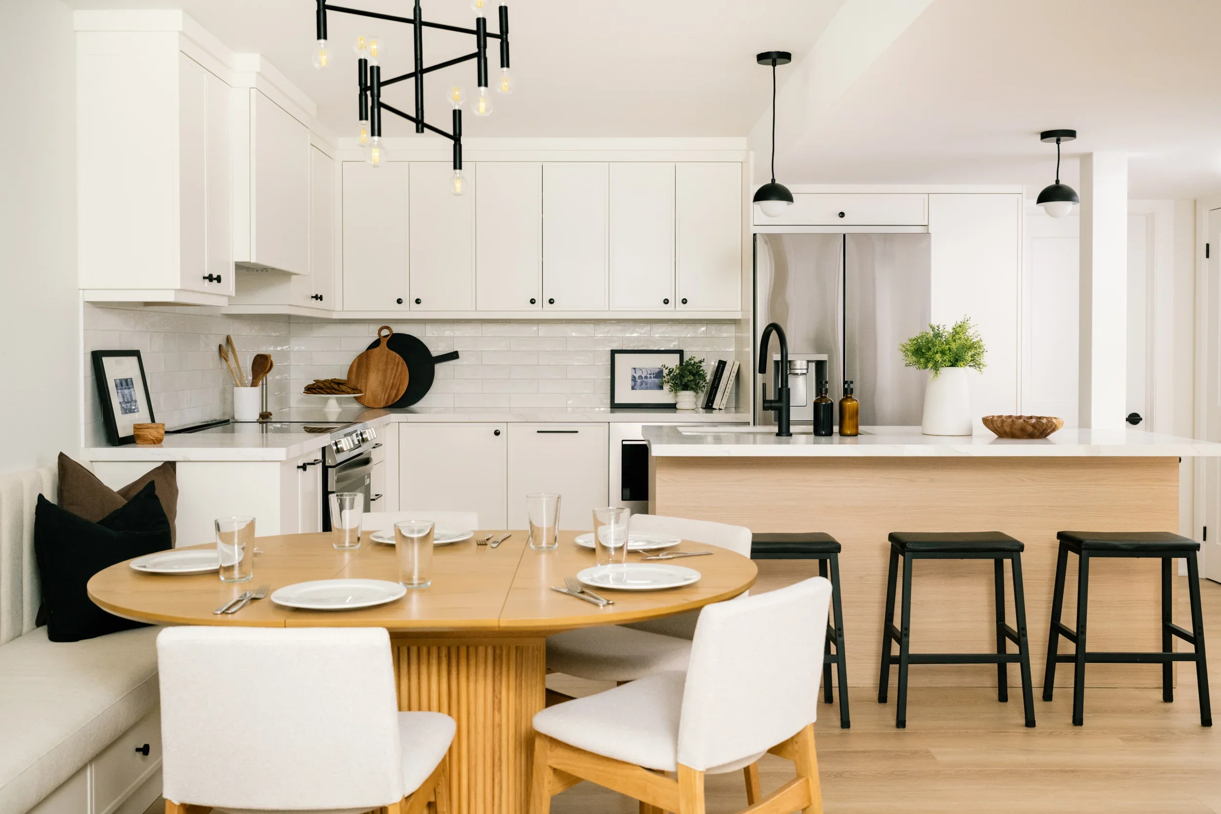 A dining area and white kitchen with a kitchen island in a basement