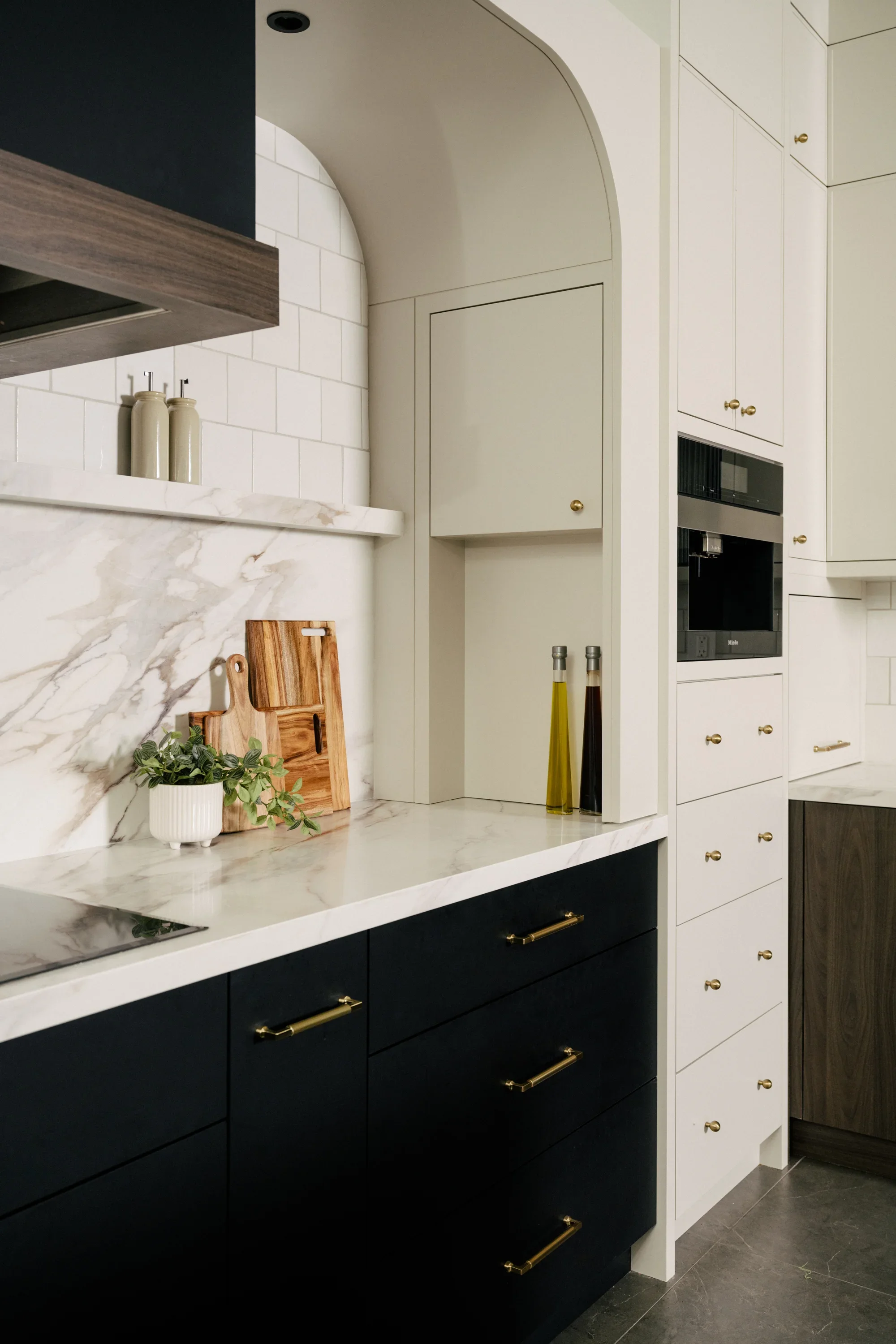 A wall niche is built into the wall beside the stove area. The niche holds bottles of vinegar and oil and a small cabinet with a door.