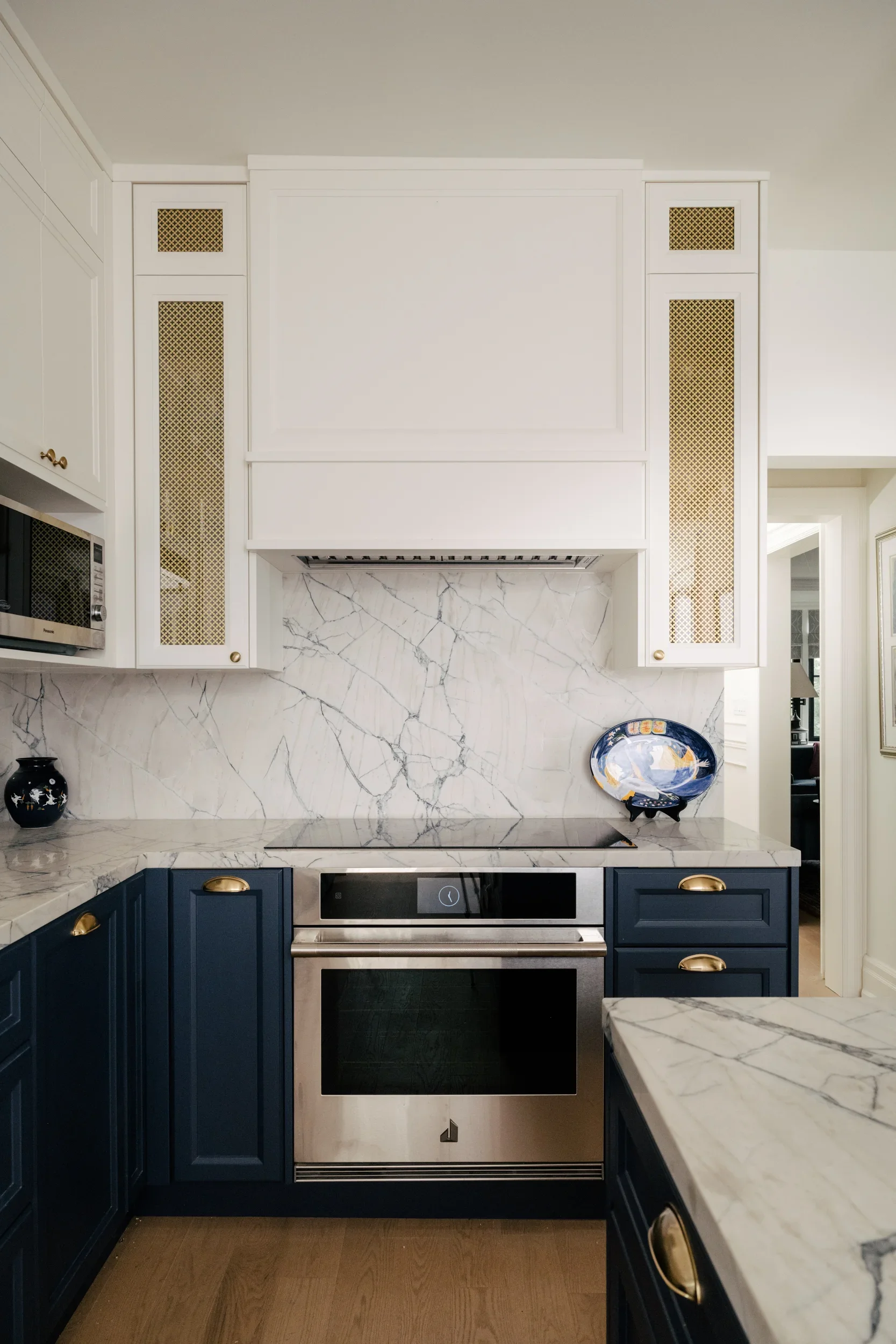 A stove with a glass stovetop in a kitchen with navy blue lower cabinets and white upper cabinets