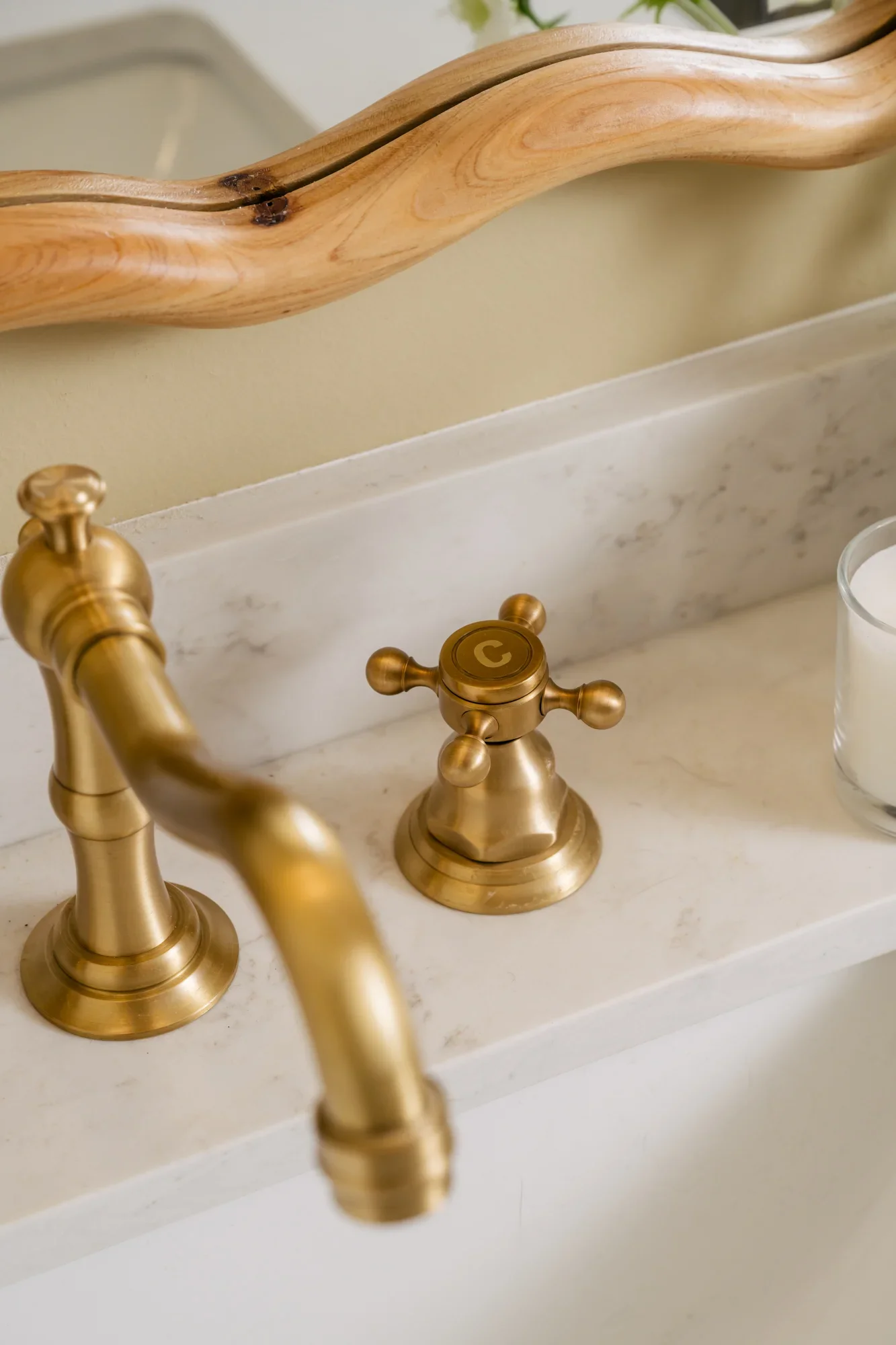 Close up of a brushed gold, cold water cross faucet knob