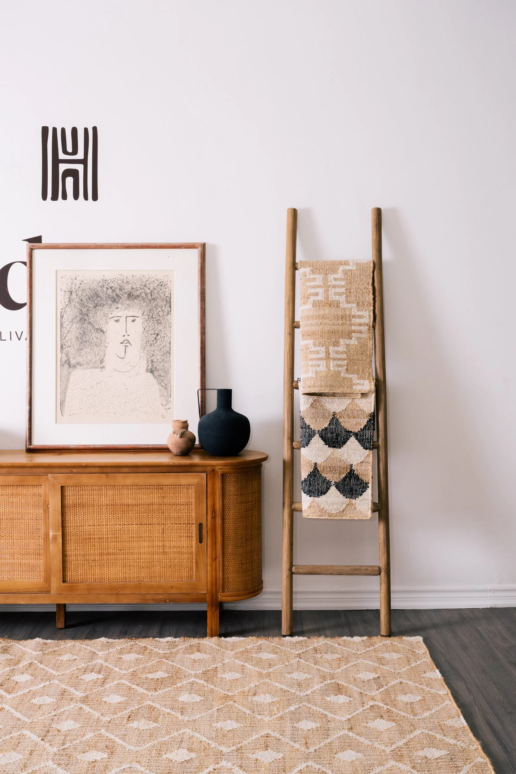 A credenza and wooden ladder stand next to each other against the wall, in front of an hd+co rug