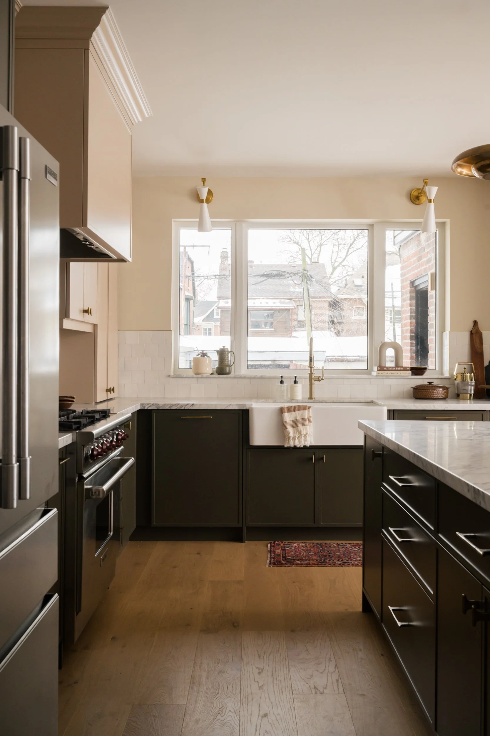 Kitchen window above large farmhouse sink with lower sage green cabinets