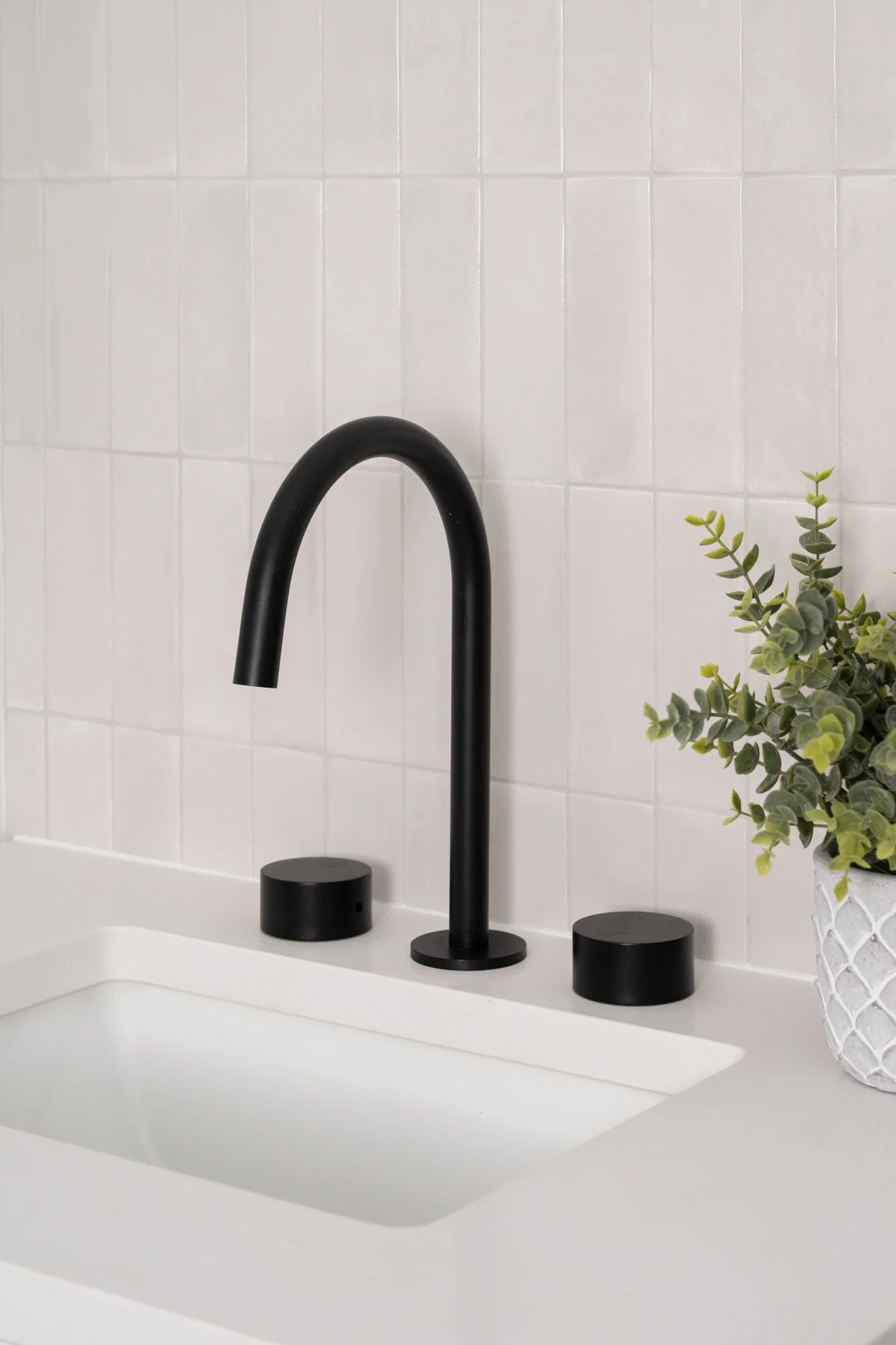 Matte black bathroom faucet and puck-shaped knobs.