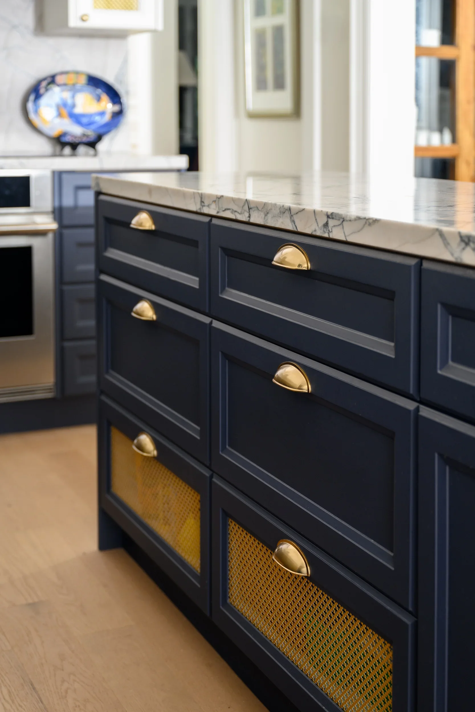 A closeup of a navy blue kitchen island and gold handles hardware