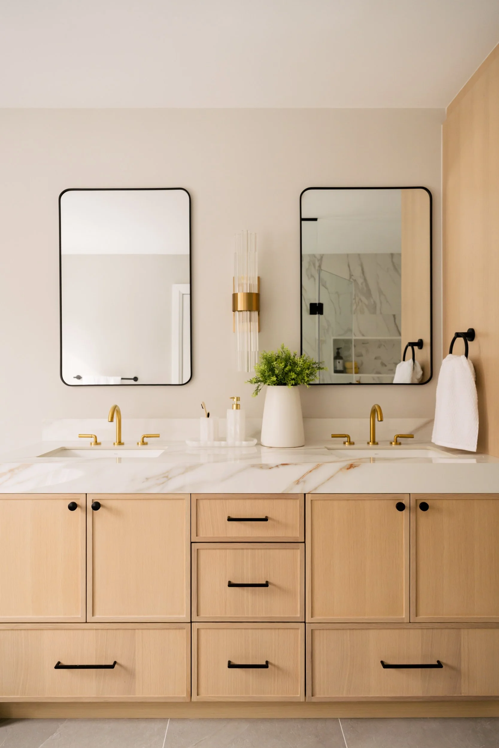 Double vanity with stone countertop, gold faucets and black cabinet hardware. and