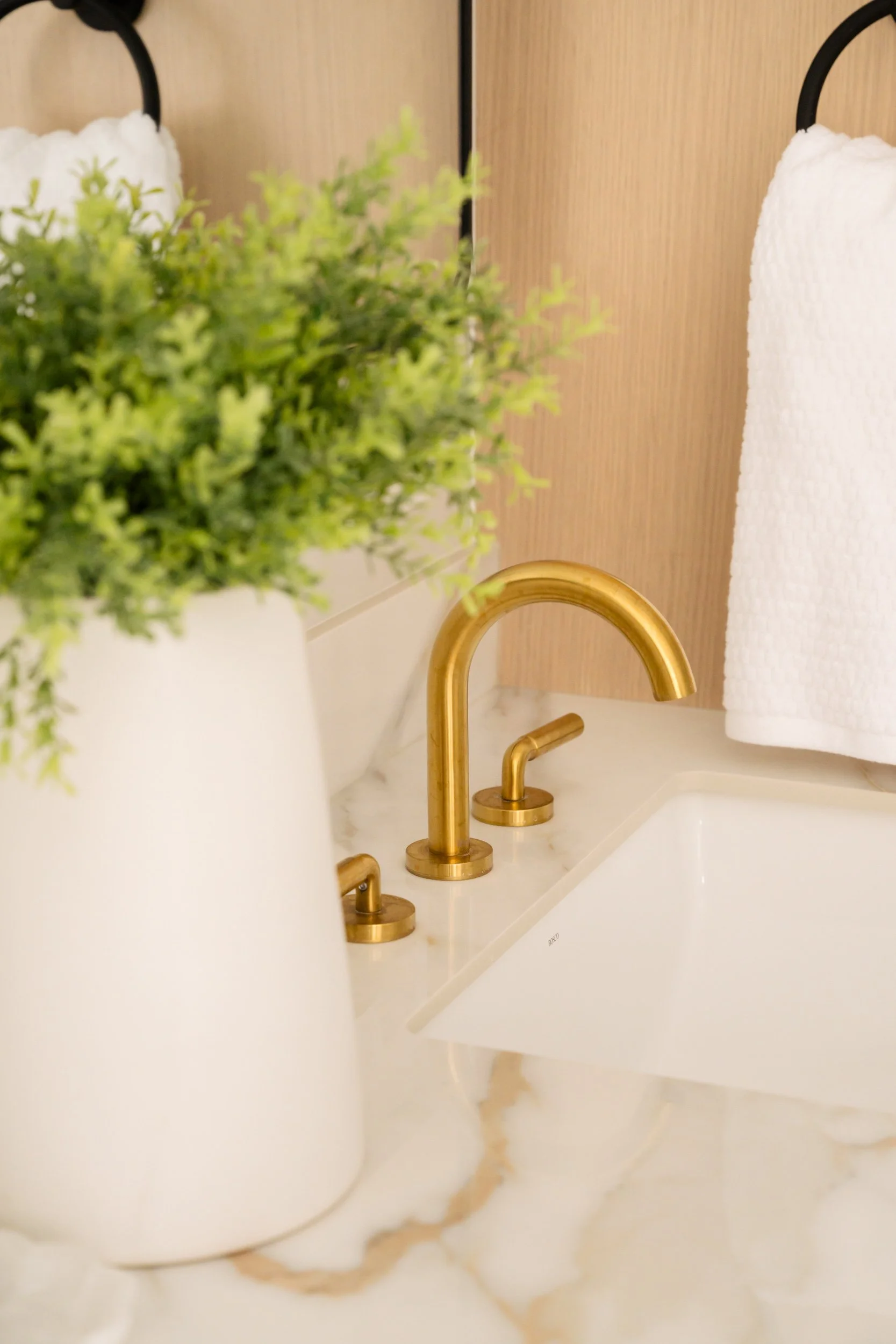 A close up of brushed gold faucet in a bathroom.