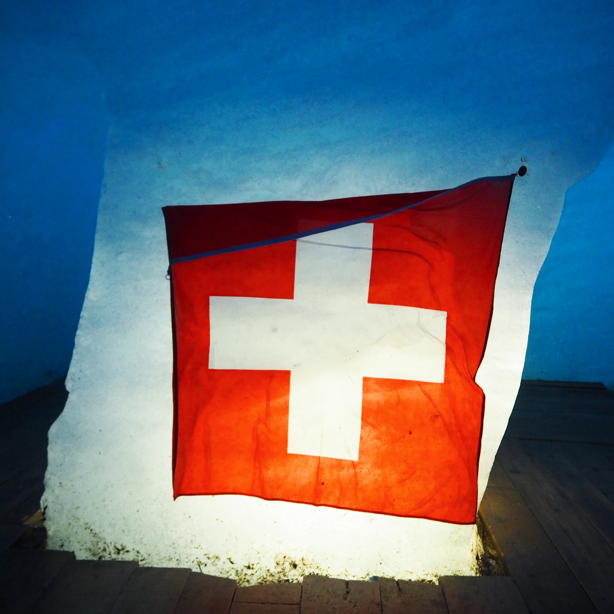 Švýcarská vlajka na konci ledového tunelu Furka, který má převýšení 2 429 m. Zajímavostí je, že se zde natáčela bondovka Goldfinger. Swiss flag at the end of an icy tunnel which has 2 429 m cant. The interesting fact is that the movie Goldfinger from Bond series was filmed there. 