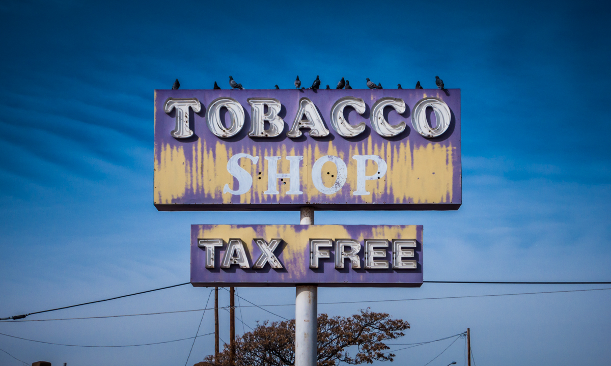 A small, boarded-up shack accompanies this large and rather attractive sign at the corner of two US highways in Española.
