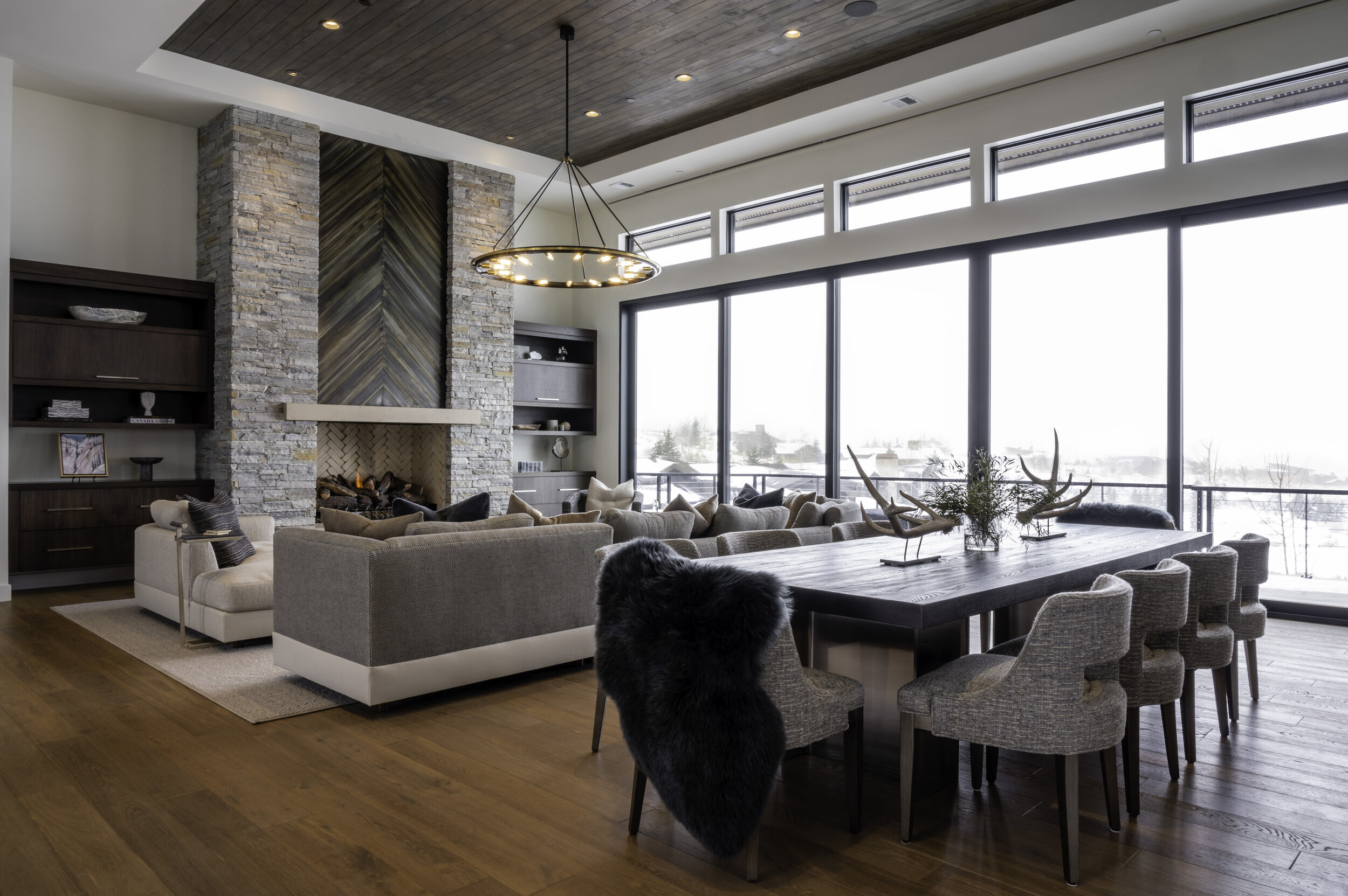 Mountain home great room with stone fireplace and a wall of windows