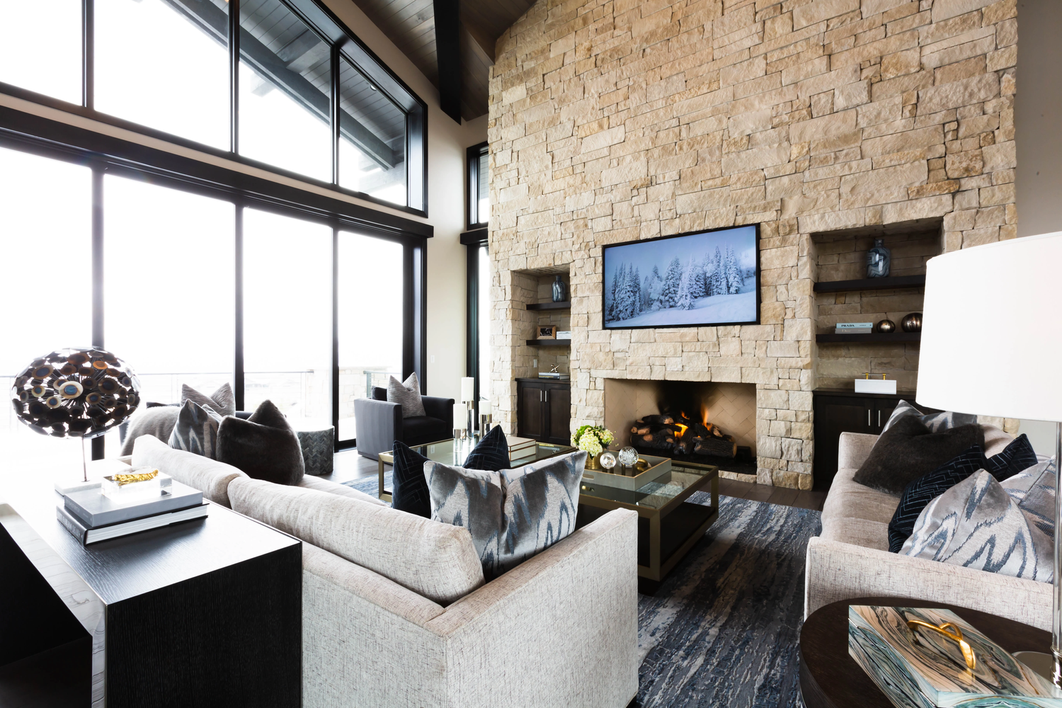 Living room with stone fireplace and floor to ceiling windows