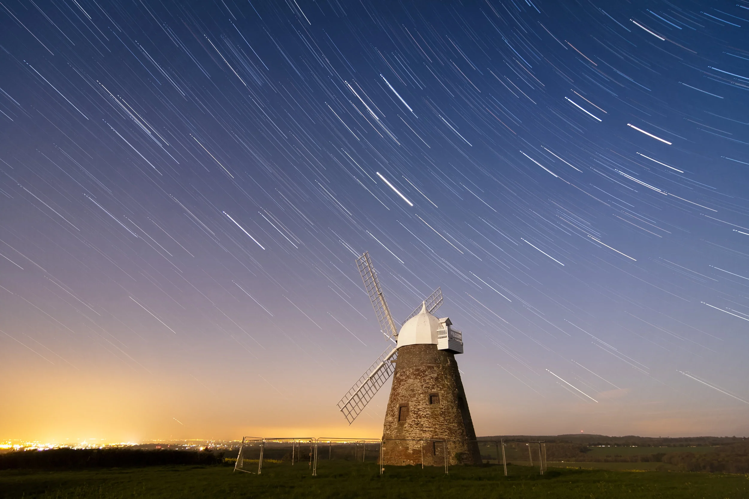 The shutter stop controls the length of time the light sensor is exposed to the light. The photograph above allows for a long exposure creating the streaking star effect in the sky above the windmill. Since the windmill is stationary the light, although over a prolonged period of time, is emitted and recorded from the same space. In contrast, as the Earth rotates, the stars in the sky move in relation to the camera, thus changing position of the light source along the direction of the Earth’s rotation. Image Attribution: “ While the sky whirls away ” by sagesolar is licensed under CC BY 2.0