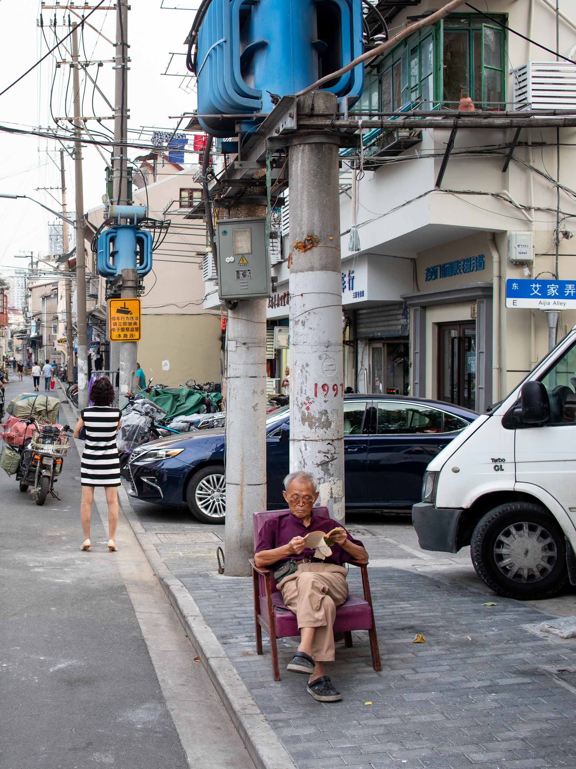 Old man reads a book on street in Shanghai, China.