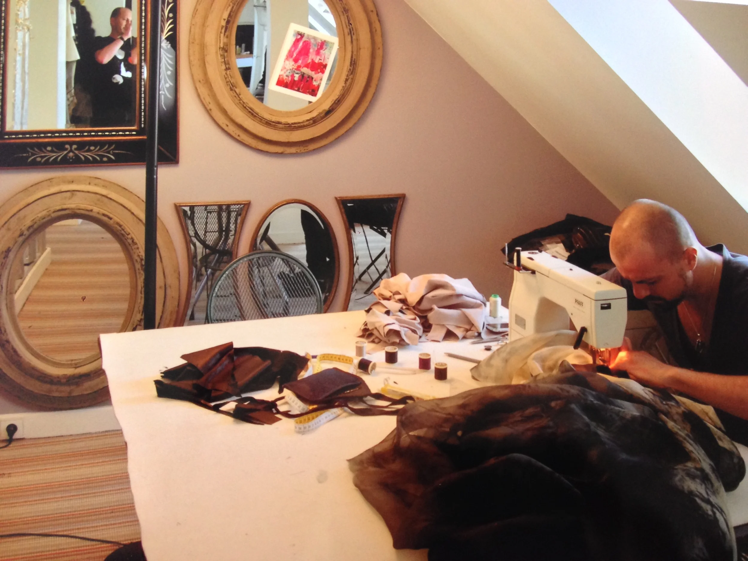 Jean-Luc Sanhes and Julien Fournié in the fashion designer's workshop. On the mirror, a photo of a painting of Jean-Luc. PARIS, 2010