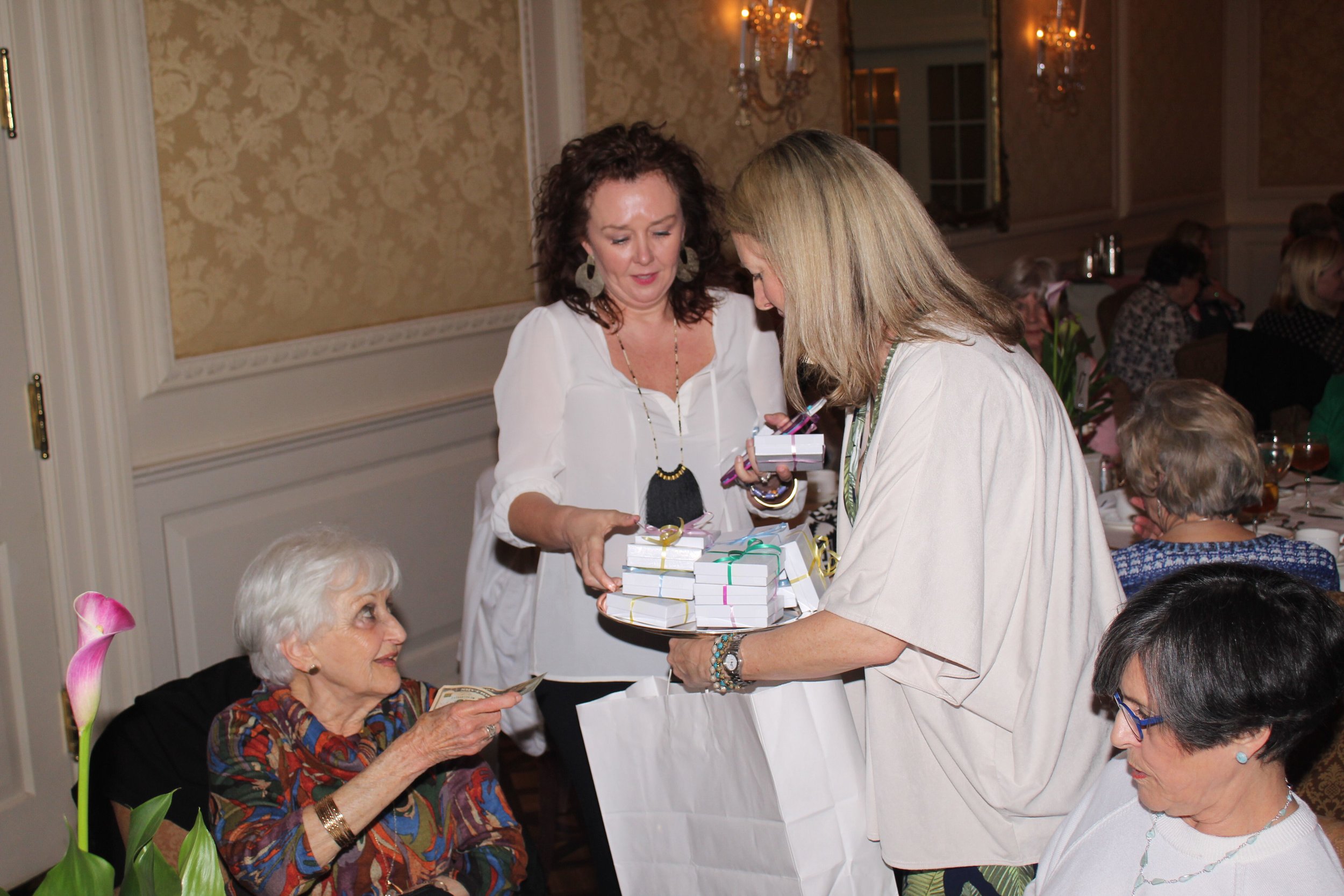 Kirstan Hamilton and Tricia Jetton sell bracelets from Fashion & Compassion during the Mystery Box raffle