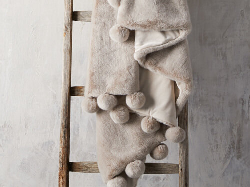   FAUX FUR POM THROW: Available in Grey (shown), Ivory or Wolf Grey. $169. Arhaus.   