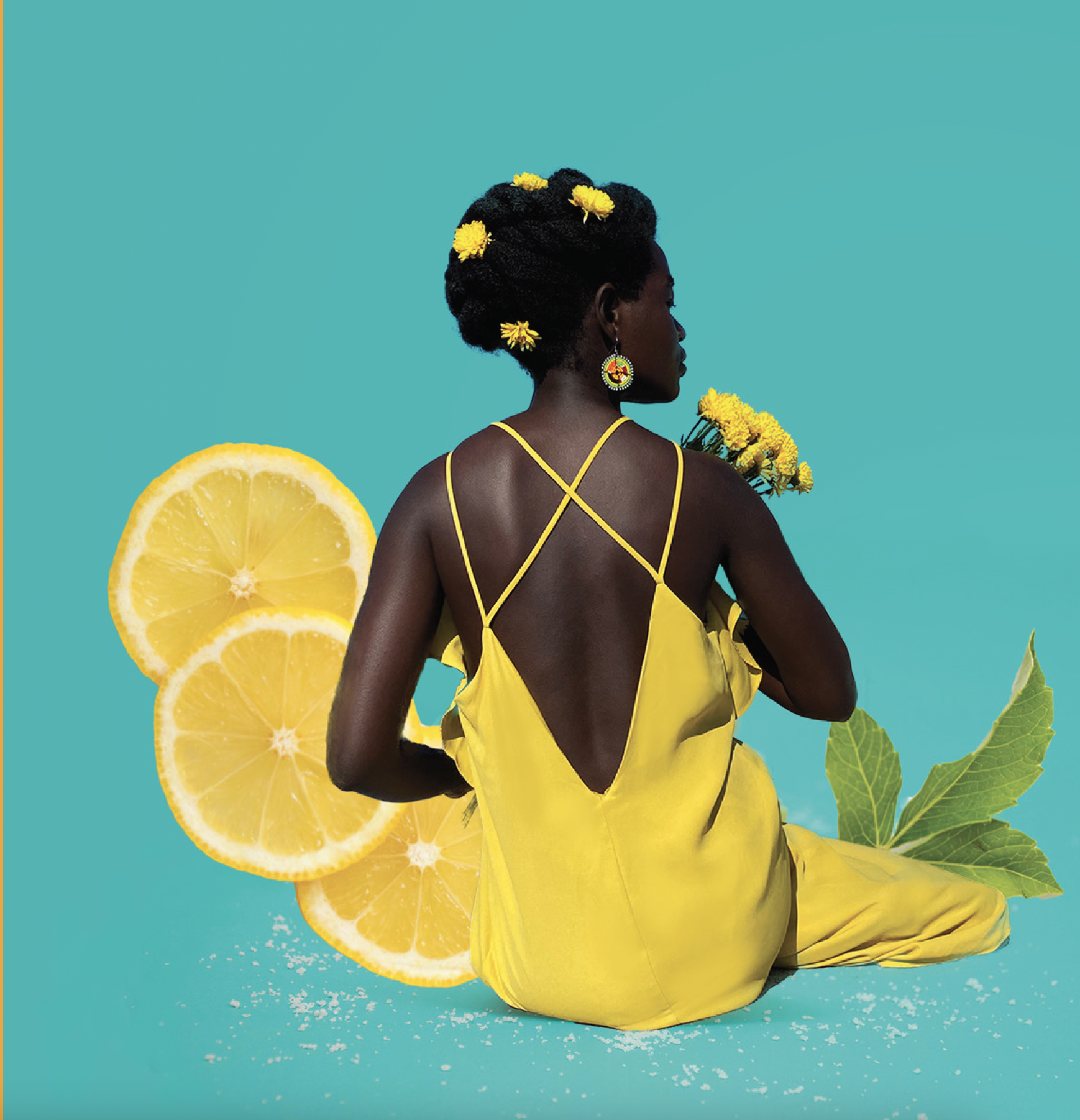 A woman with dark skin and braided hair adorned with yellow flowers, sitting against a blue background. She wears a yellow dress with a deep back and thin cross-straps, holding a bouquet of yellow flowers. There are lemon slices, green leaves, and white scattered particles around her.