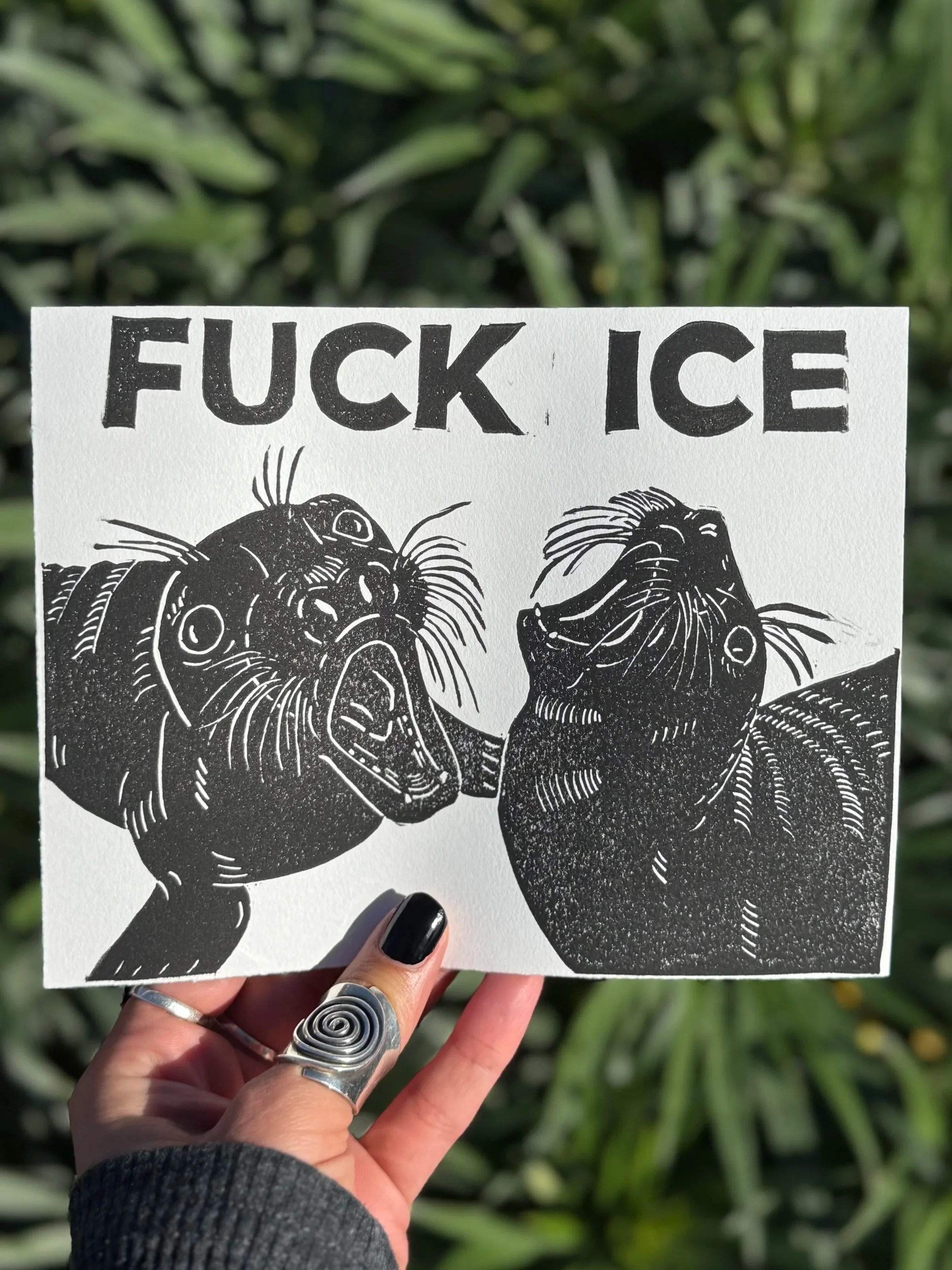 Black and white linoprint of two elephant seal pups throwing their heads back and screaming "FUCK ICE"