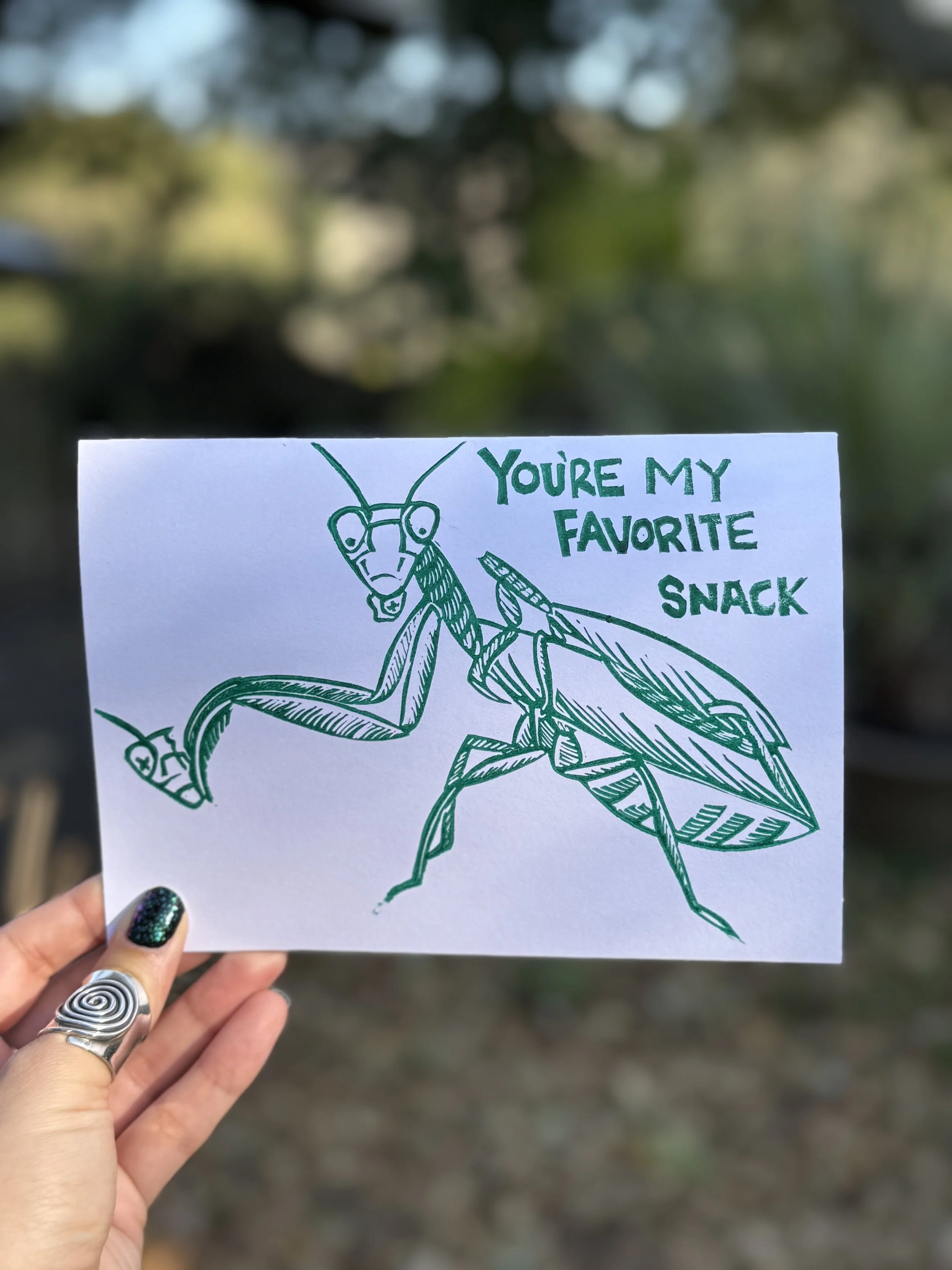 A green linoprint of a female praying mantis with a decapitated male on her back while she eats a portion of the head in her front claws