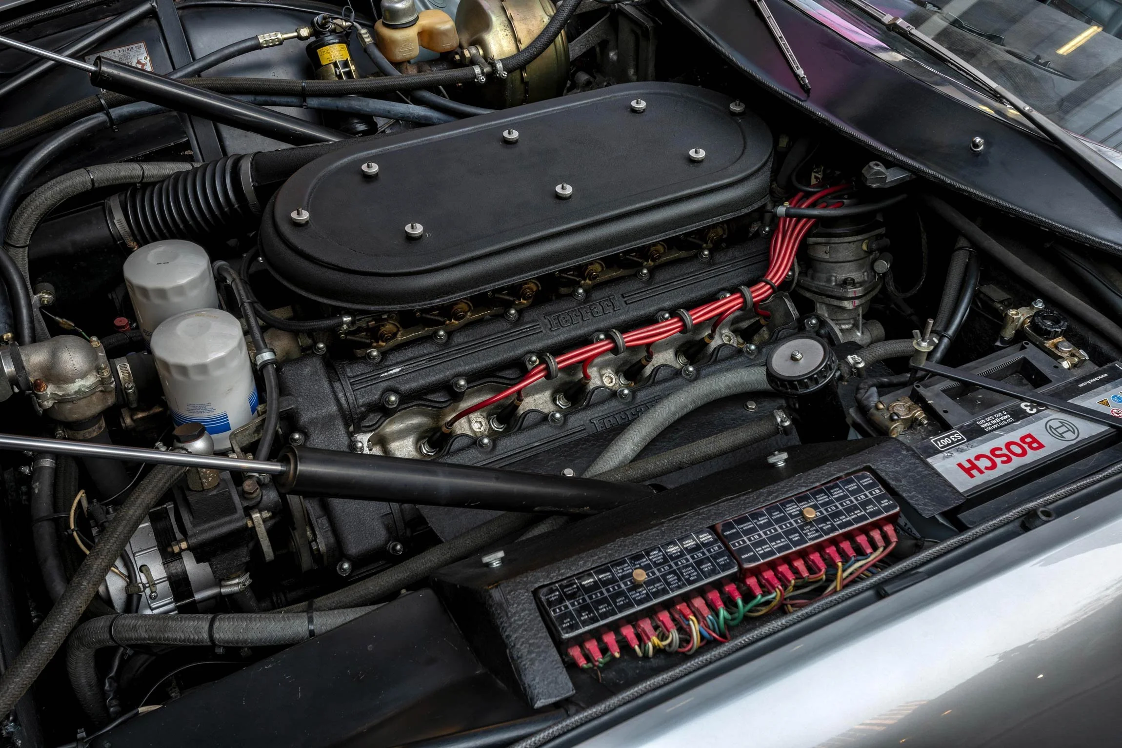 Detailed view of the Ferrari Daytona classic V12 engine bay showing wiring and components during a London photoshoot