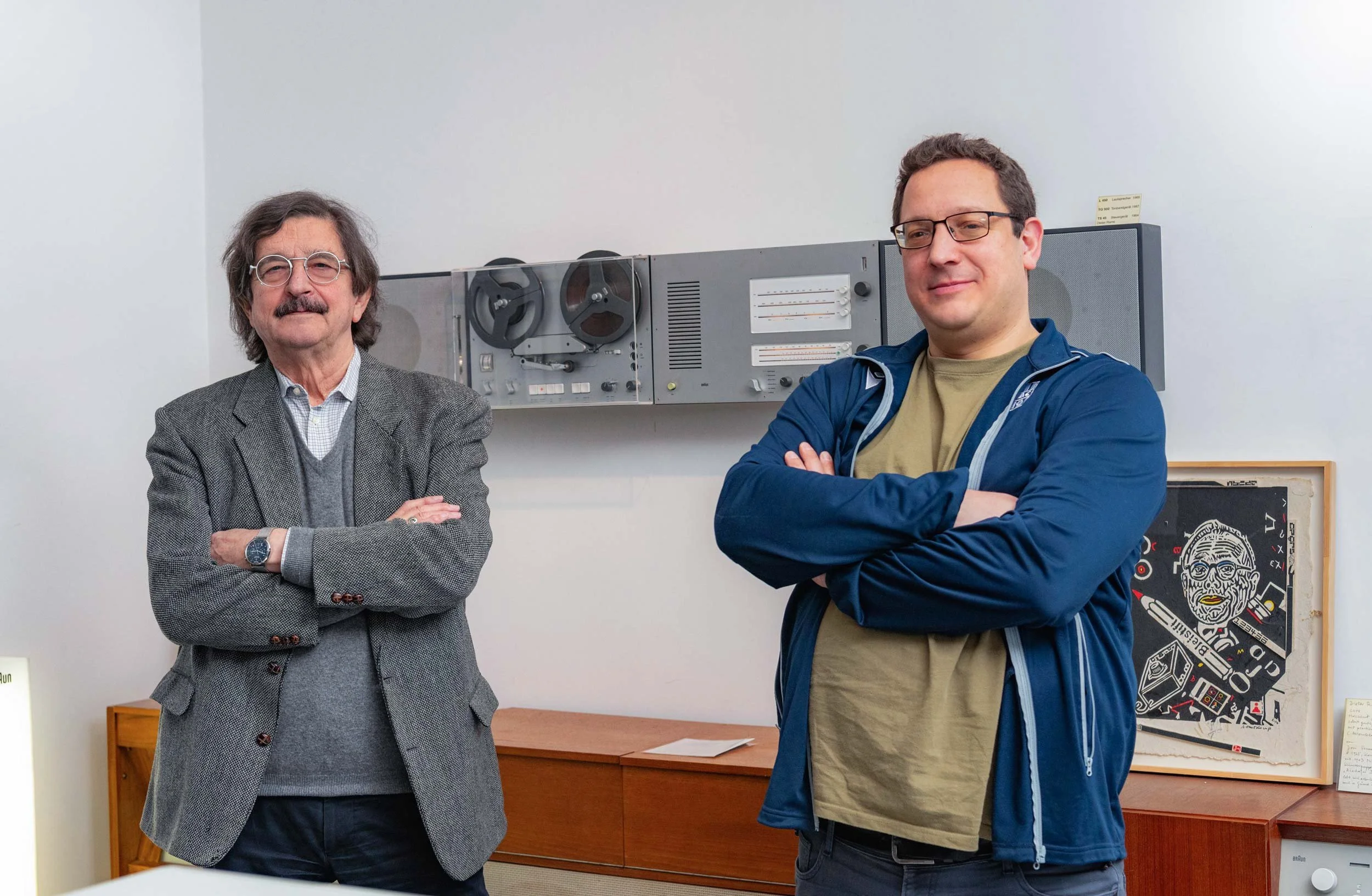 Werner Ettel and Simon Krohn photographed together beside historic Braun reel-to-reel audio equipment in the design collection.
