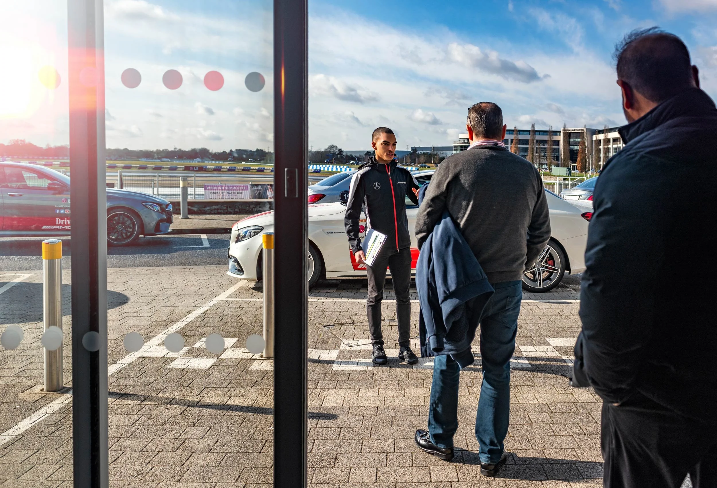 Mercedes-AMG instructor briefing guests in the paddock at Mercedes-Benz World
