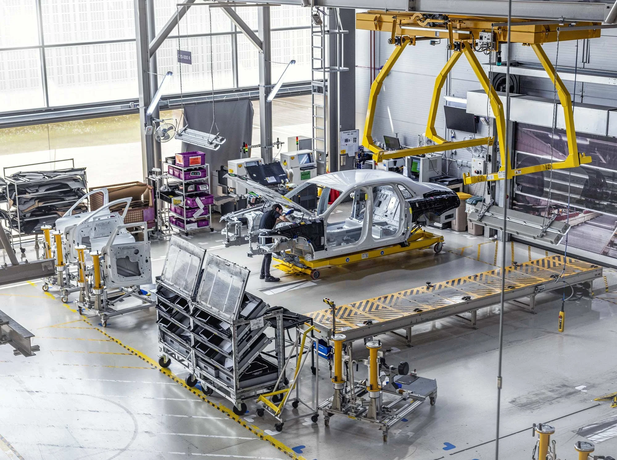 Wide view of luxury car shell on production line inside vast hangar-style manufacturing plant – industrial photographer London