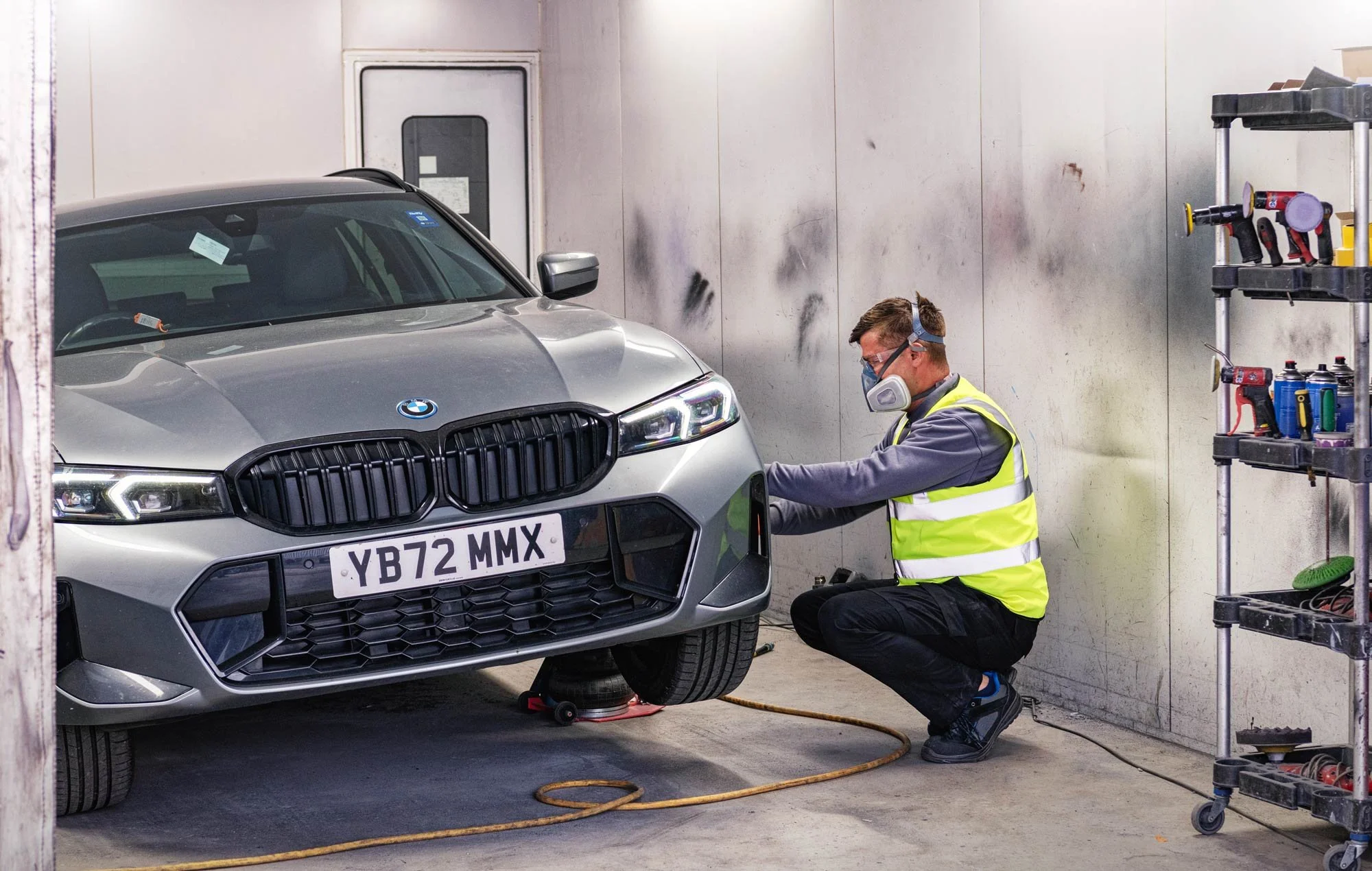 Technician in high-visibility vest working on a car in a professional workshop – workshop photography London