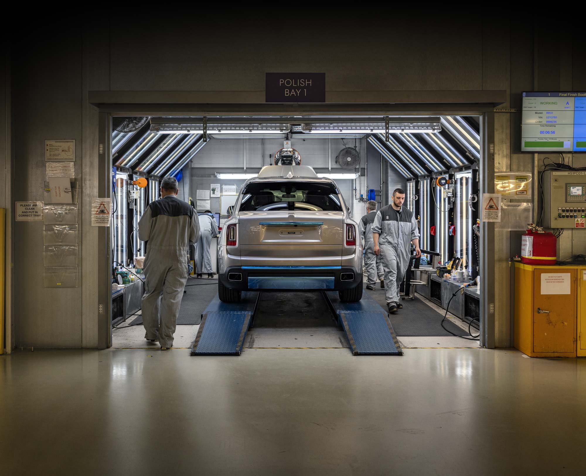 Workers polishing a luxury car inside a dedicated LED-lit booth in a high-end manufacturing facility – industrial photographer London