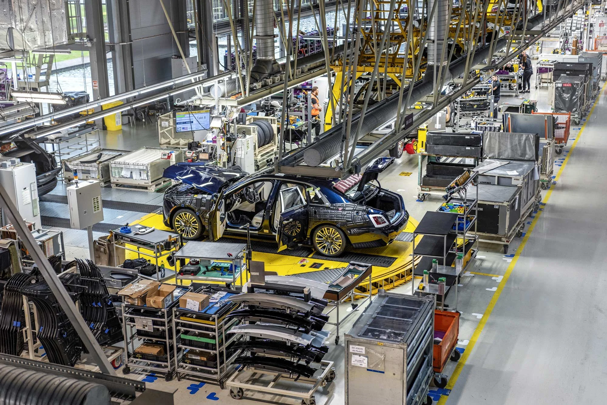 Elevated wide view of large-scale production line with high-end vehicles on robotic arms – industrial manufacturing photography London