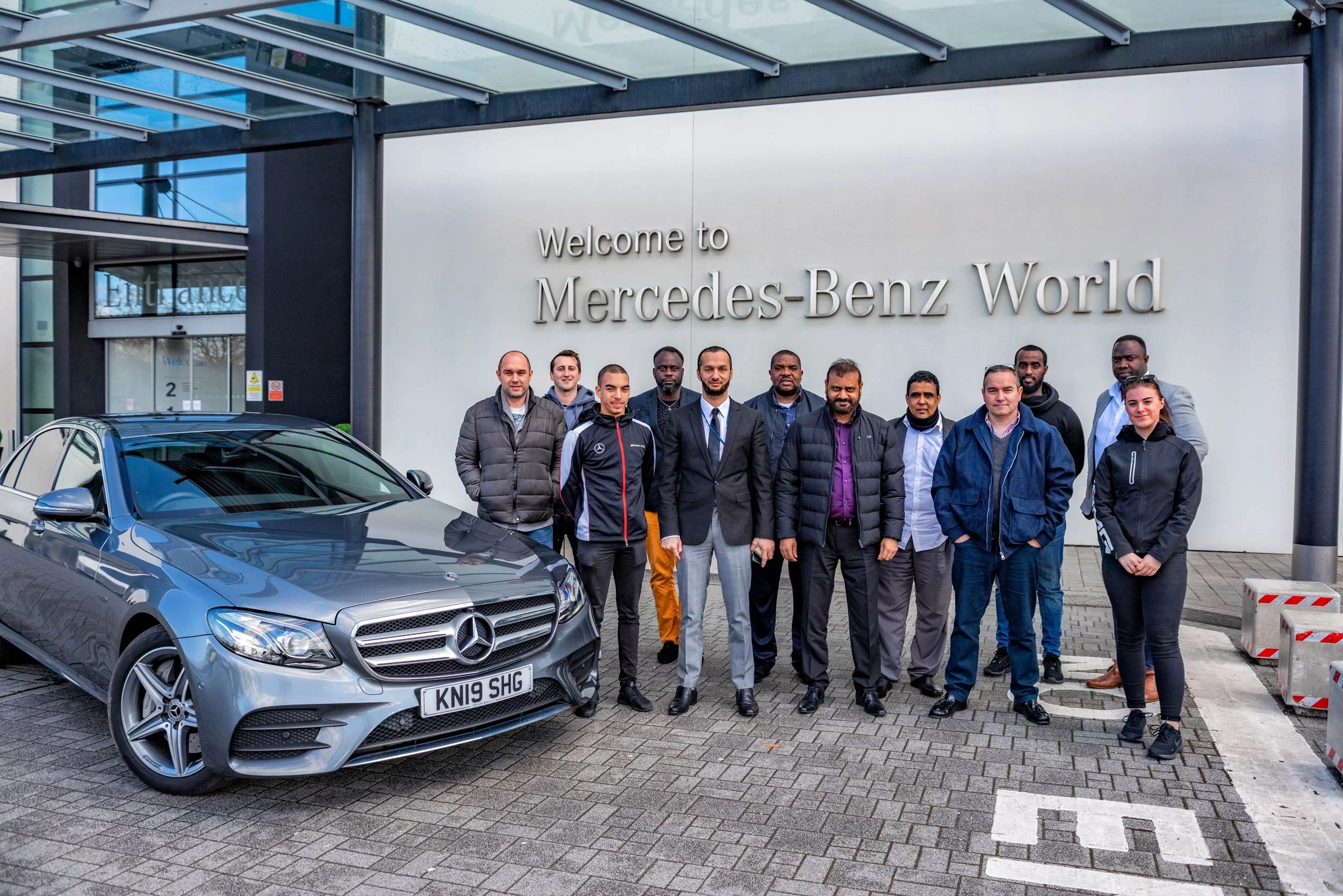 Bolt drivers and Mercedes-Benz World staff grouped at the entrance with an E-Class — corporate event photography London