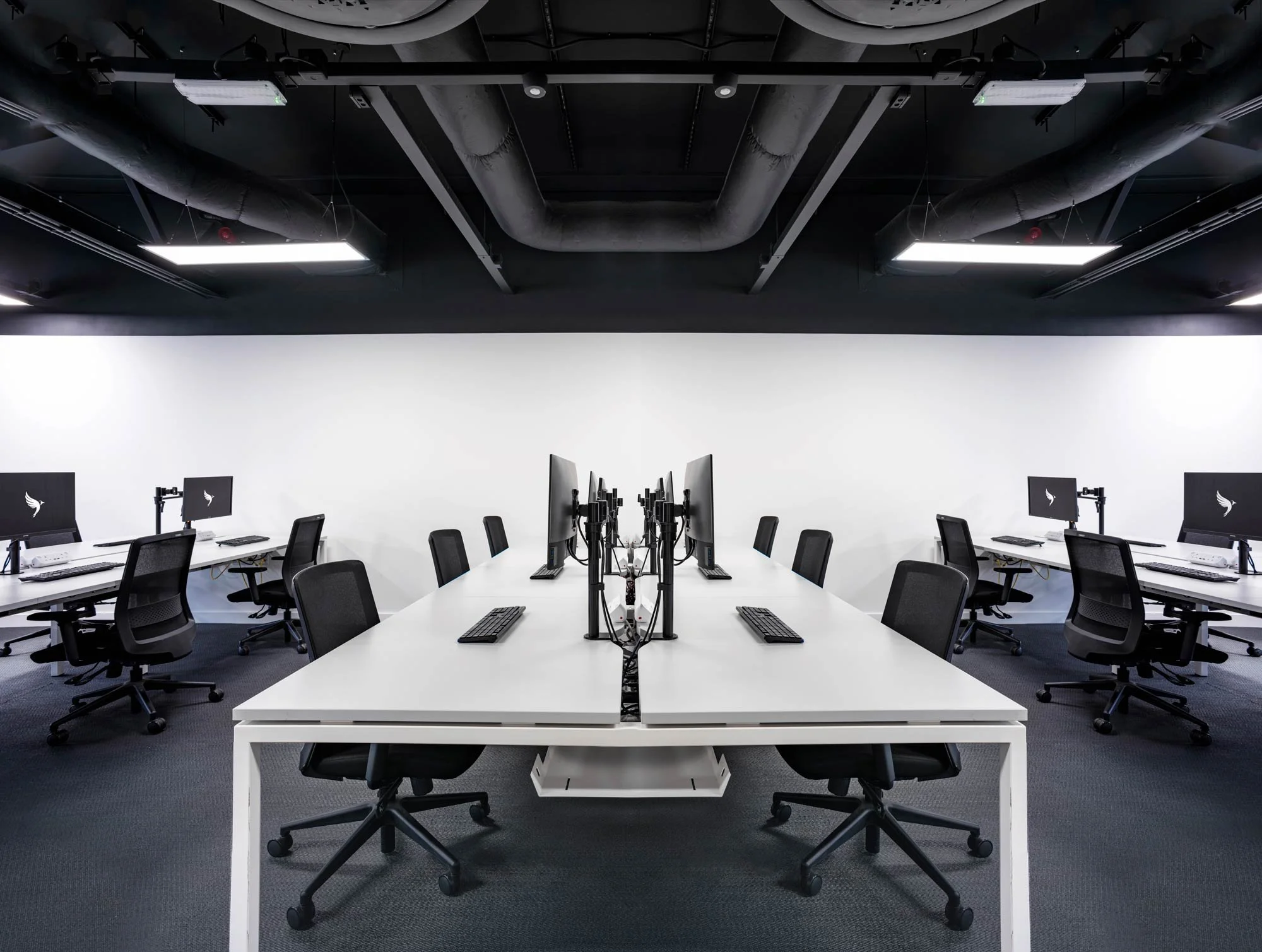 Sleek modern open-plan office interior with white desks and black chairs in corporate headquarters – industrial company office photography London