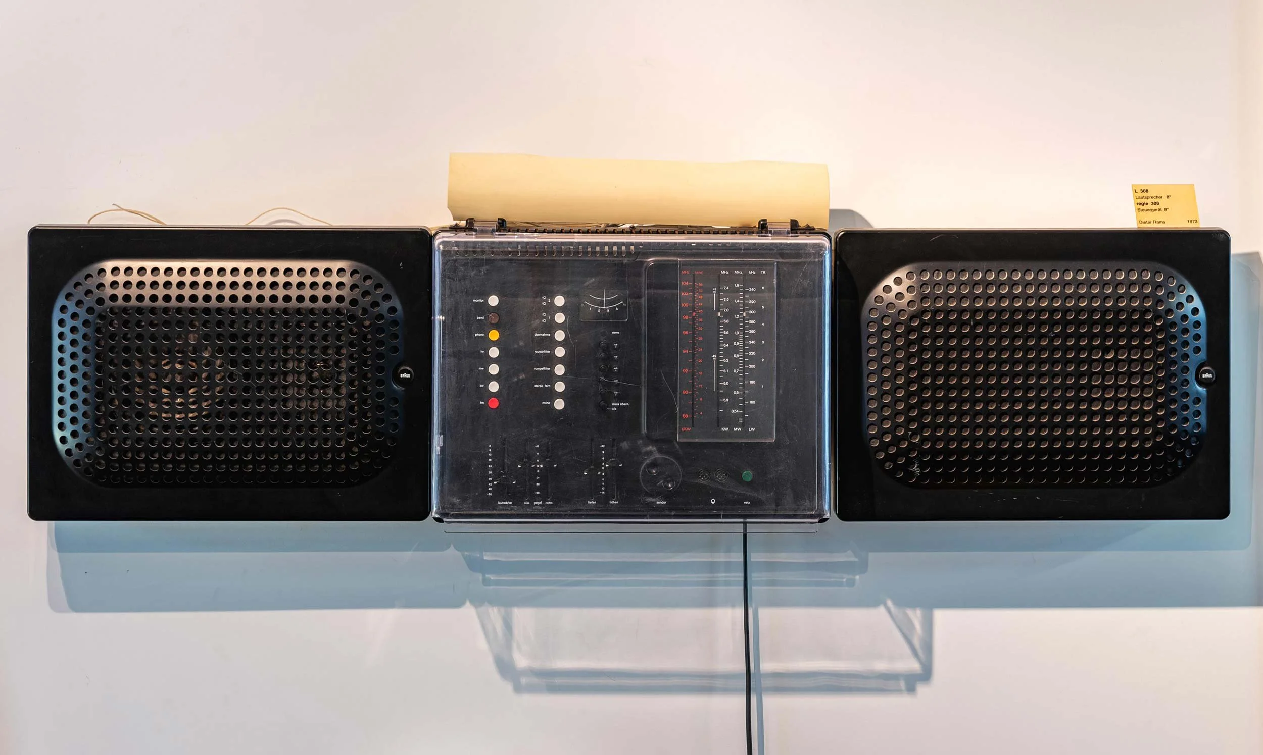 Vintage wall-mounted Braun audio system with a central radio unit and two black speakers.