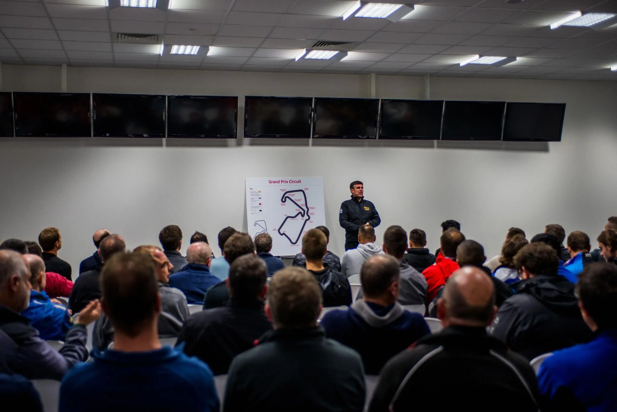 Racing team briefing in garage at Silverstone track with formula car – behind the scenes automotive events photography London