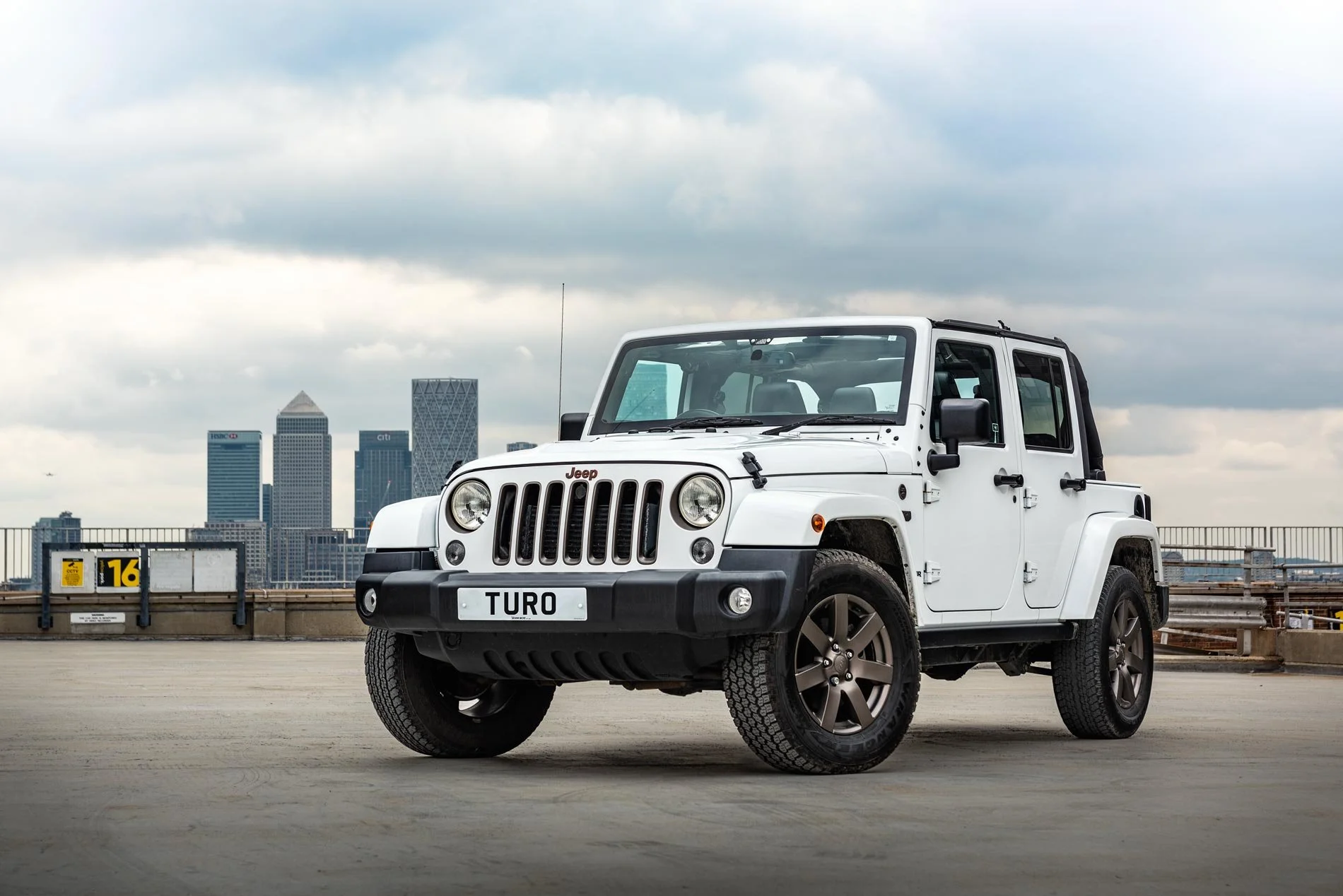 White Jeep Wrangler on London rooftop with Canary Wharf