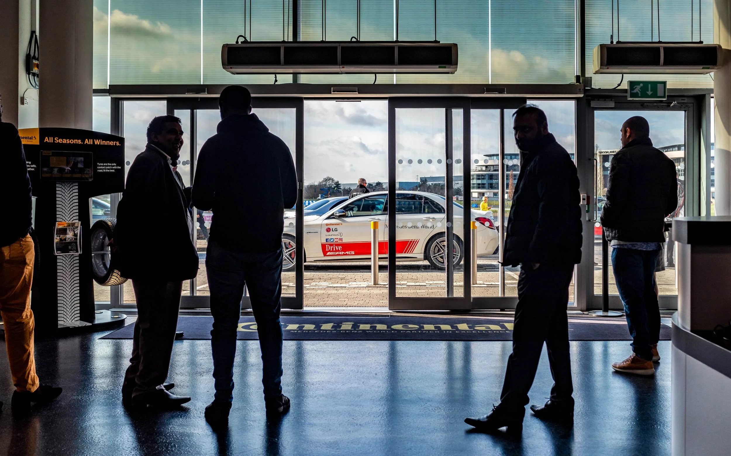 Drivers waiting in the Mercedes-Benz World lobby looking out to the paddock — corporate event photographer London