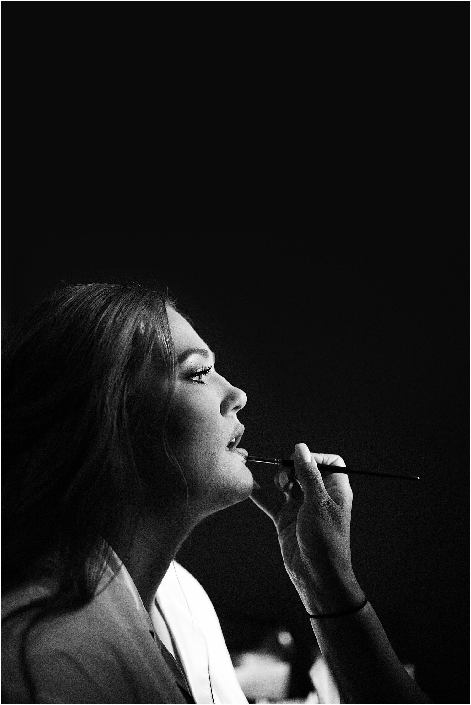 bride getting her makeup done in moody lighting