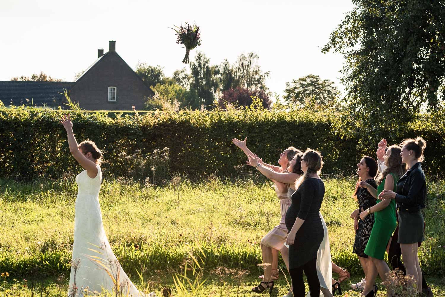 Gooien van het bruidsboeket, door bruidsfotograaf Cfoto tijdens huwelijk op Benedensas