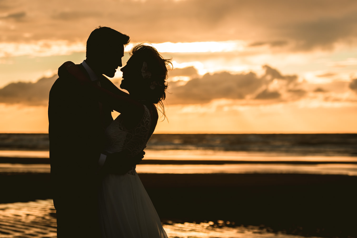 spontaan moment aan het strand bij zonsondergang tijdens bruidsr