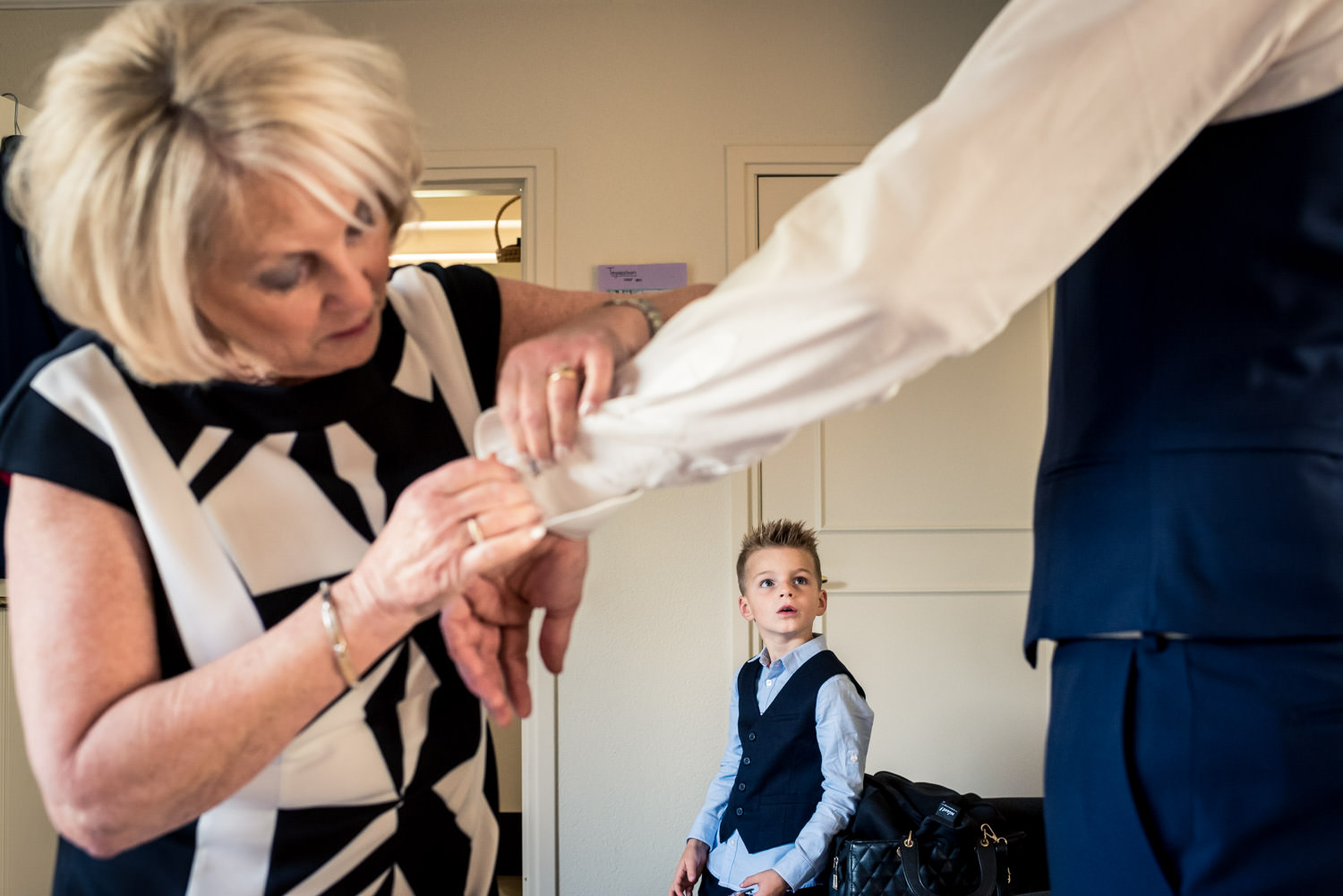 Cfoto legt vast als de moeder helpt de bruidegom bij aankleden,
