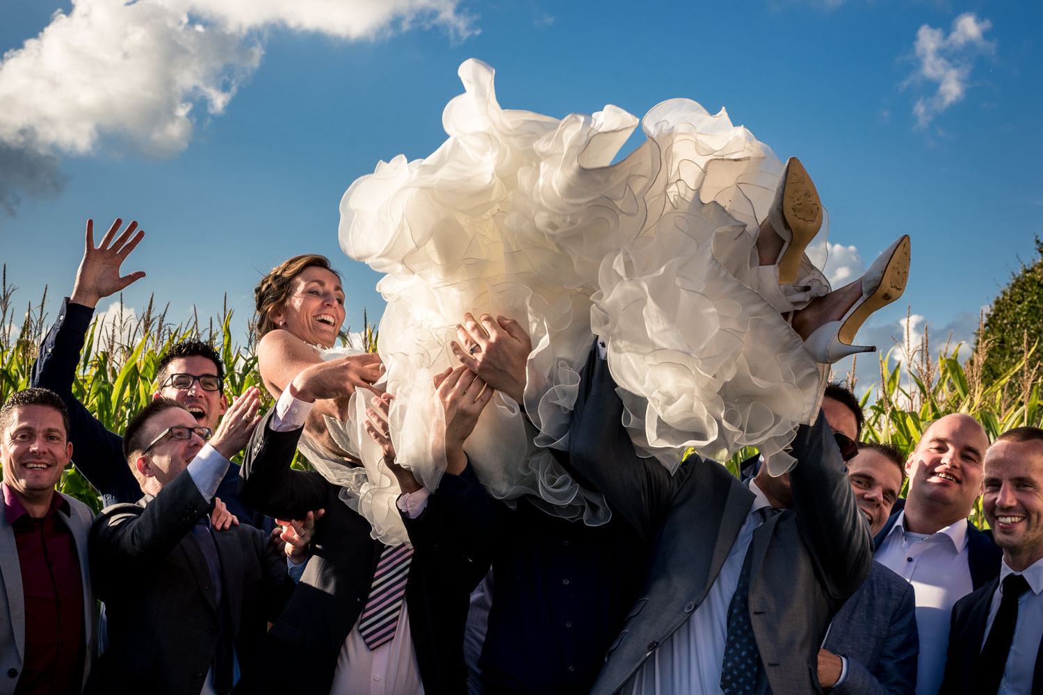 Huwelijksfotografie de groepsfoto van de bruid die omhoog gegooi