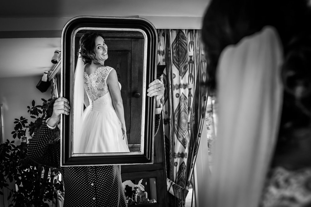 bruidsfotograaf maakt foto als de bruid in de spiegel kijkt