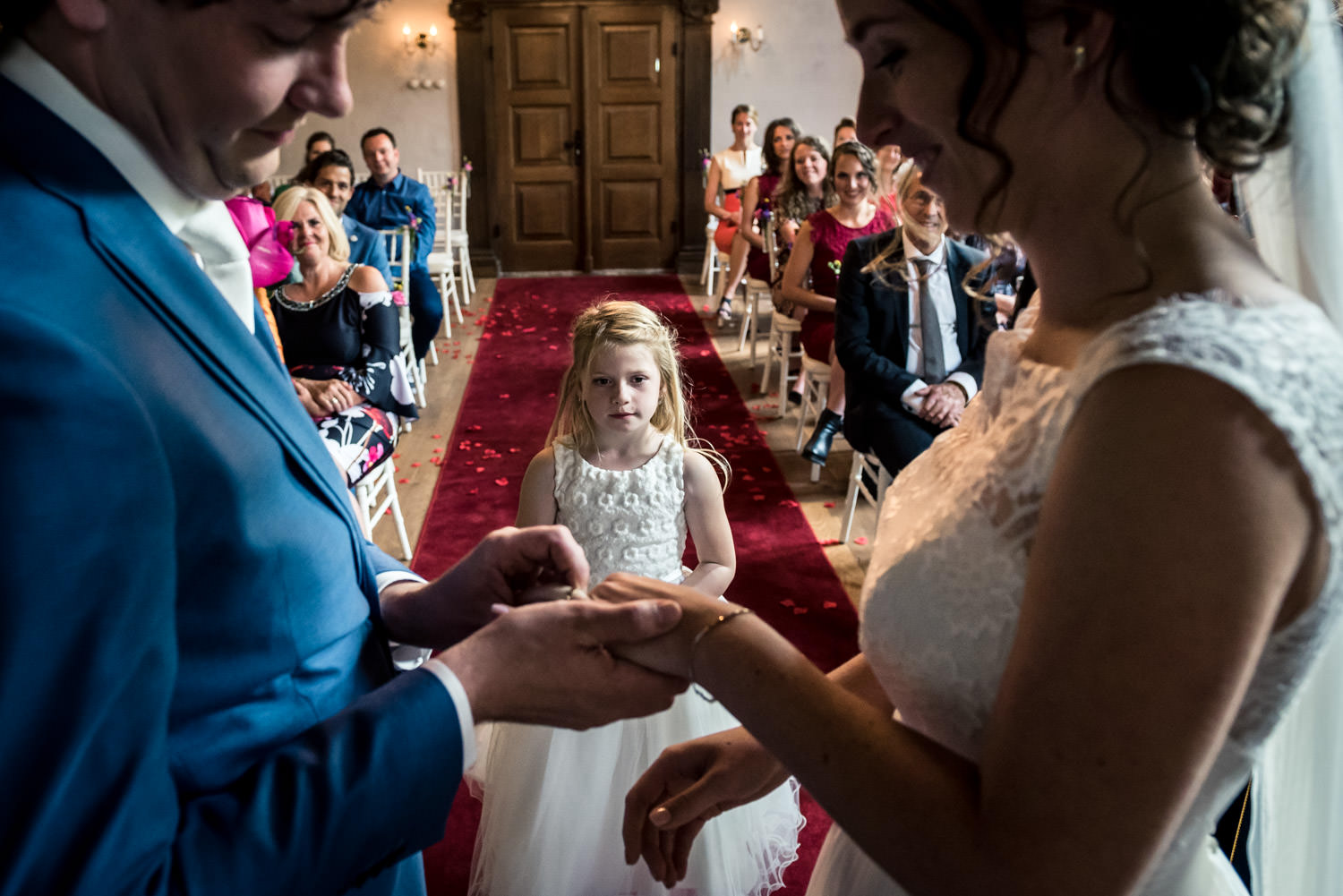 bruidsmeisje geeft de ringen tijdens de ceremonie op kasteel dus